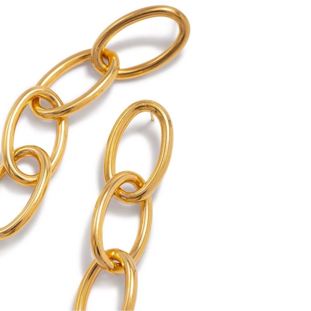 Close-up of a shiny gold chain featuring large, elongated oval links connected in a series. The chain is arranged with some links overlapping, set against a plain white background.