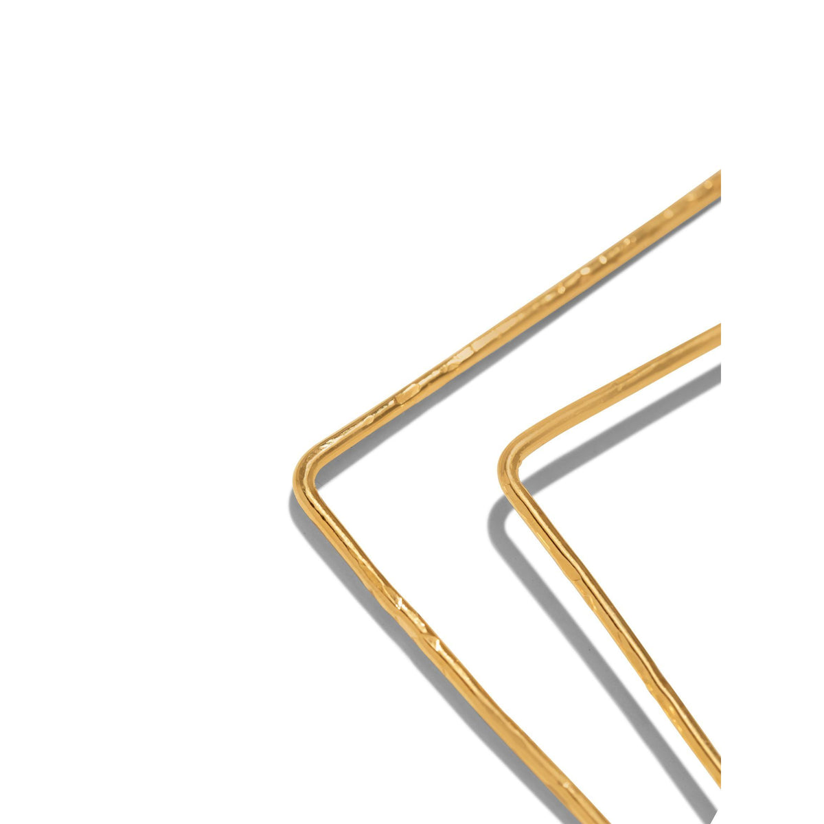 gros plan of JAREDJAMIN Bijoux en Ligne's or Squaretastic créole Post boucles d'oreilles, showing two thin, 18K plaqué or wire frames avec a texturé, artisanal look et overlapping corners casting soft shadows on white.