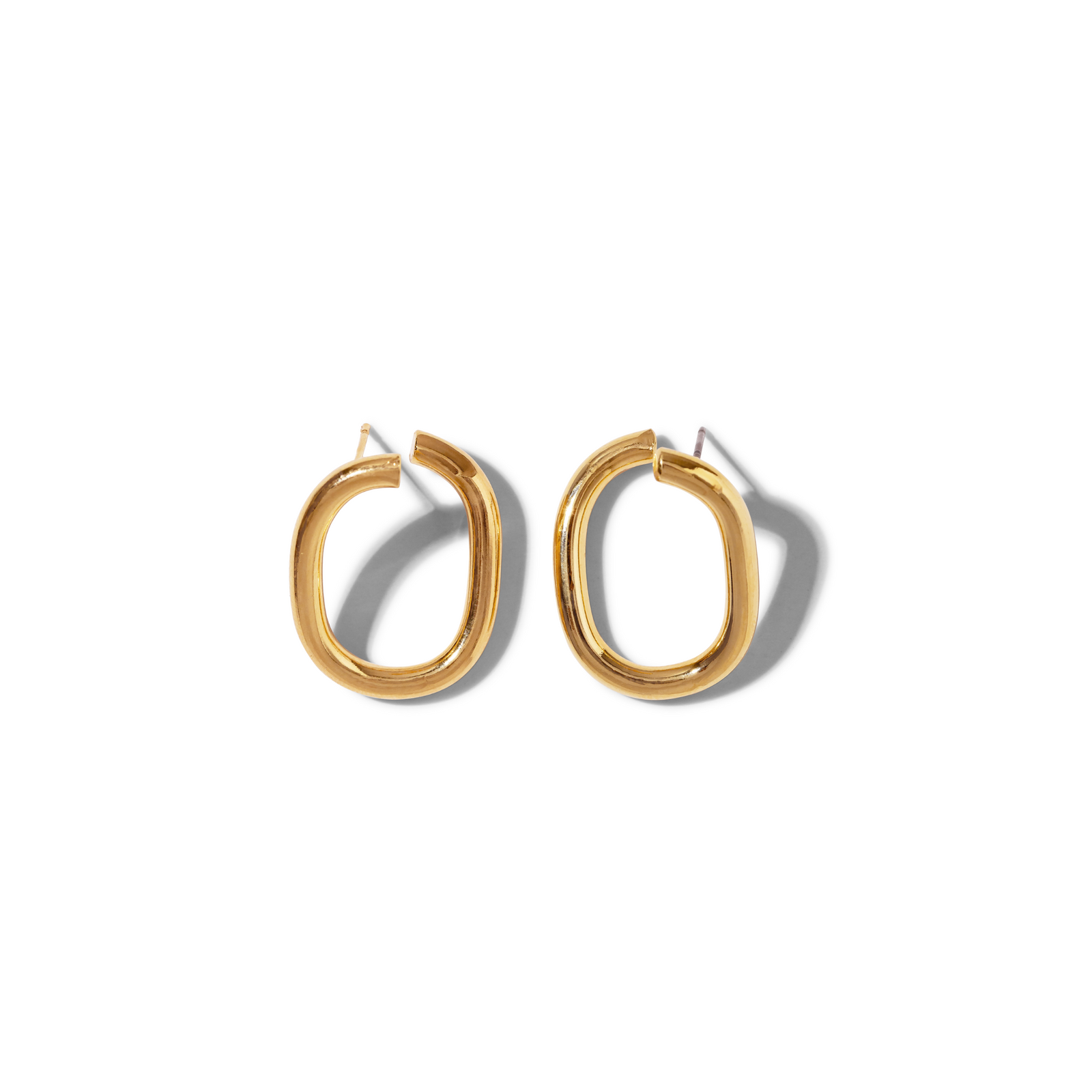 The Gold Billie Stud Post Earrings by JAREDJAMIN Jewelry Online are chunky, lightweight gold hoops with an irregular oval shape and a smooth, shiny finish. Shown side by side on a white background, they cast soft gray shadows to the right.