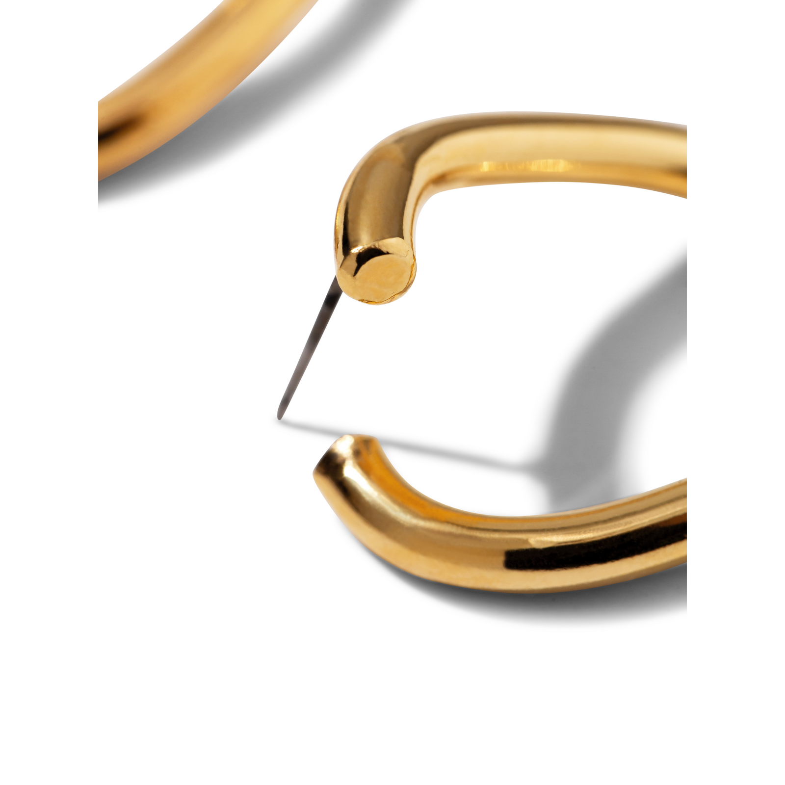 The Gold Billie Stud Post Earrings by JAREDJAMIN Jewelry Online are chunky, lightweight gold hoops with an irregular oval shape and a smooth, shiny finish. Shown side by side on a white background, they cast soft gray shadows to the right.
