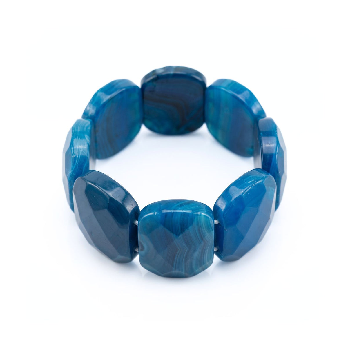 Top-down studio product shot of the Calypso gemstone cuff lying flat, displaying the circular stretch architecture and the smooth, comfortable inner edges of the blue agate plaques.