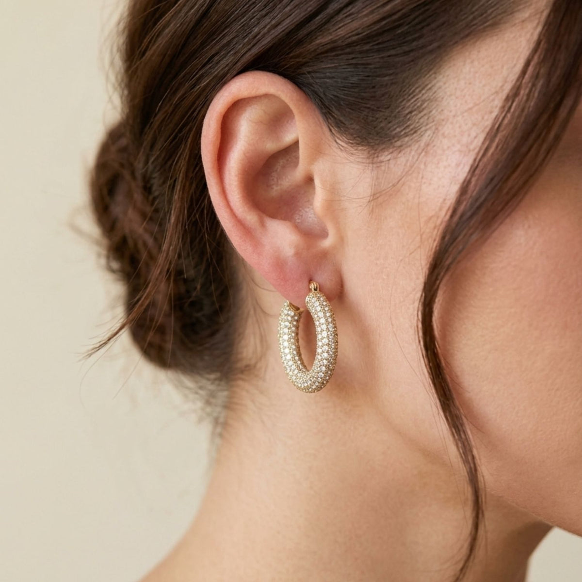 Side view portrait of a model wearing the 1-inch gold-toned Aria Pavé Chubby Hoop Earring, demonstrating its plush 5mm thickness and light-diffusing pave setting.