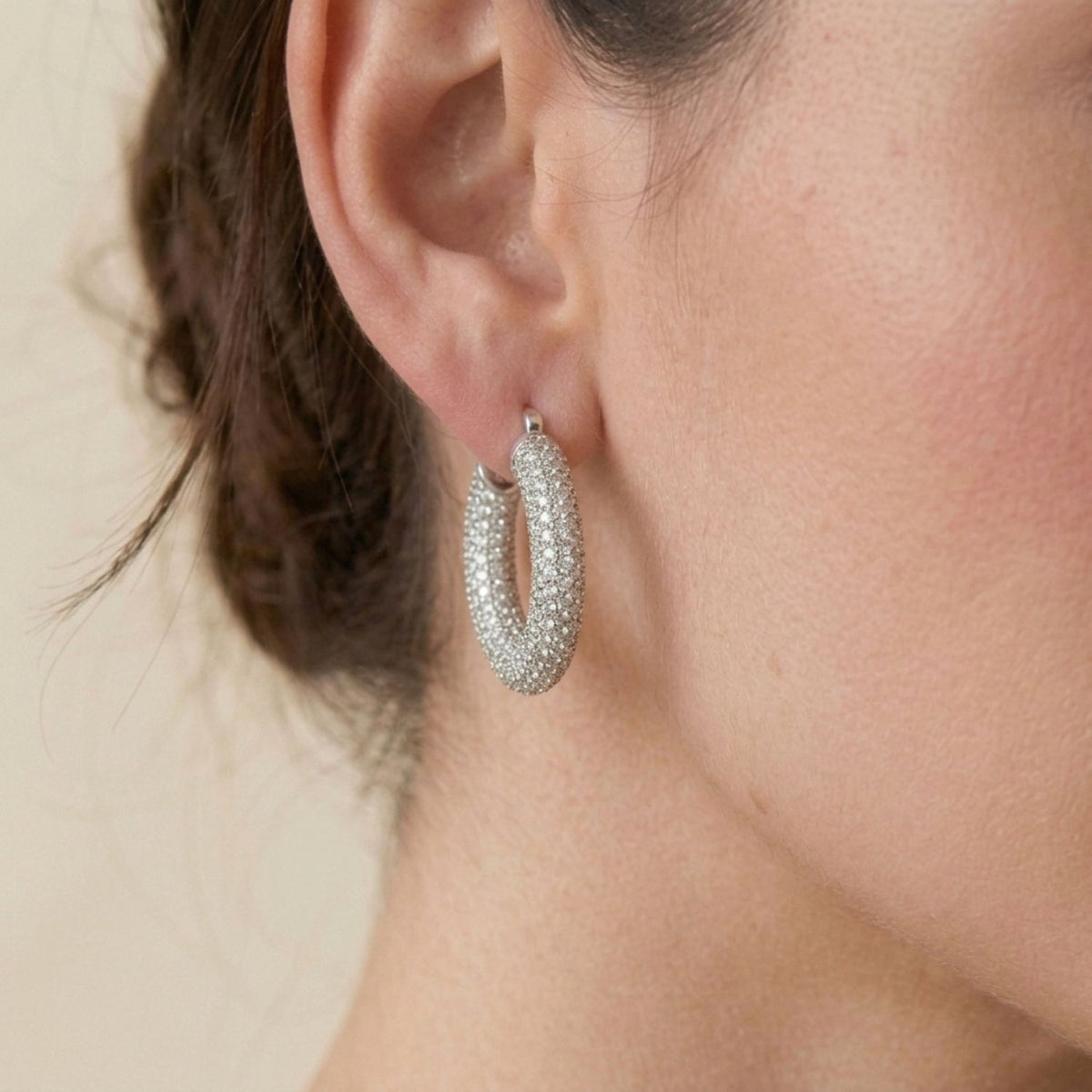 Side view portrait of a model wearing the 1-inch silver-plated Aria Pavé Chubby Hoop Earring, showcasing its 8g weighted fit along the earlobe and brilliant CZ shimmer.