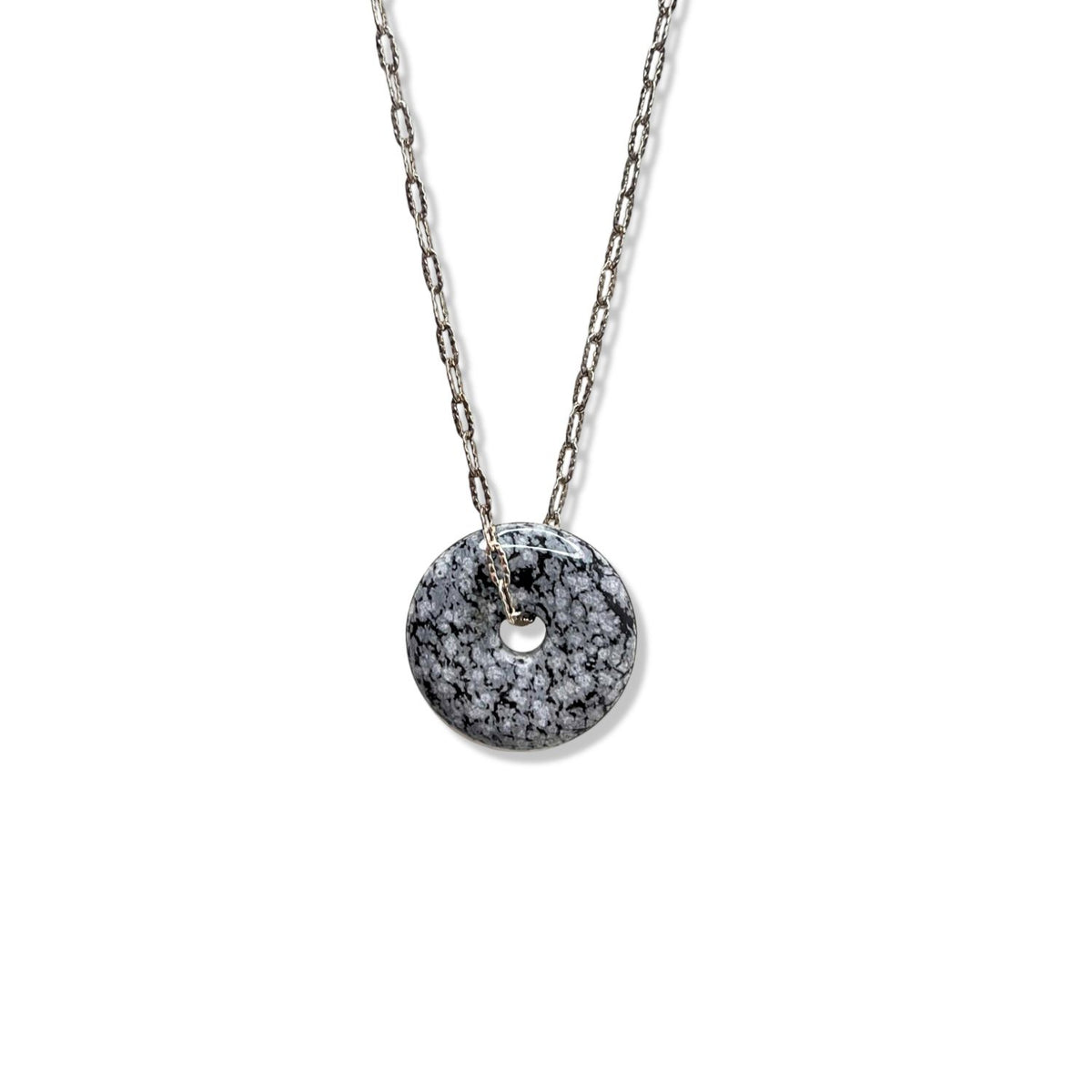 The Ash and Or Sterling Silver Necklace by JAREDJAMIN Jewelry Online showcases a round, flat, donut-shaped speckled black and white jasper pendant on an adjustable chain, displayed on a plain white background.