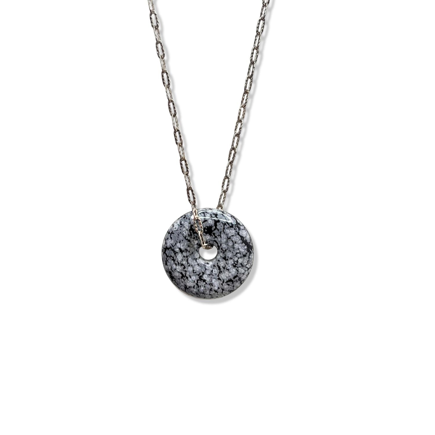 The Ash and Or Sterling Silver Necklace from JAREDJAMIN Jewelry Online showcases elongated links, a round gray-black marbled jasper pendant with a central hole, and an adjustable unclasped design with a slender bar fastening.