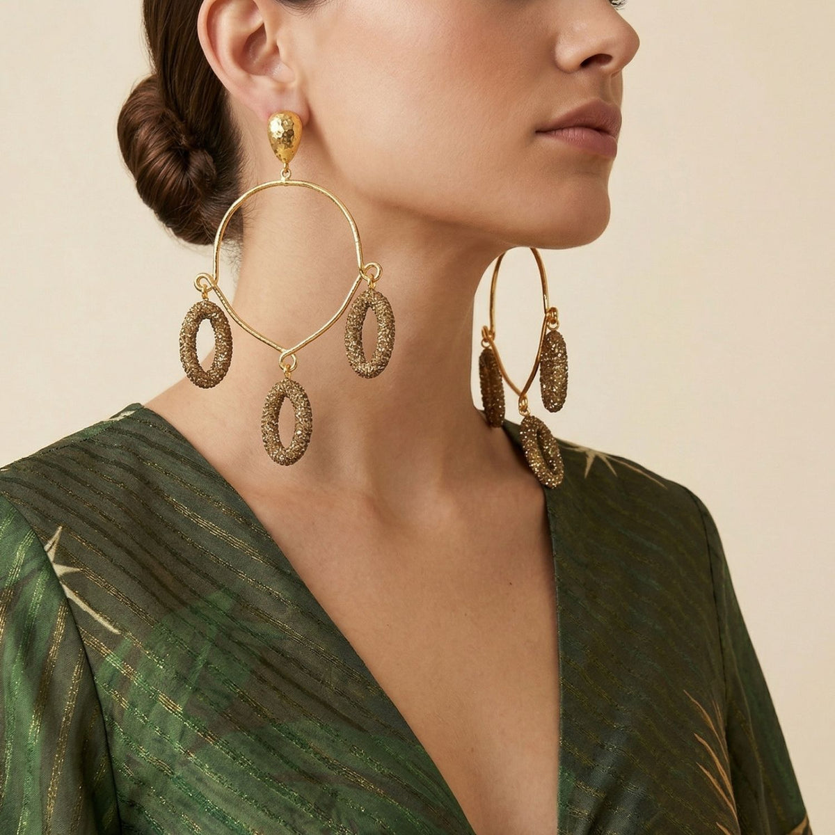 A woman with dark hair in a low bun wears JAREDJAMIN’s Aurelia Crystal Chandelier Post Earrings—three gold textured ovals, hand-assembled in our West Hollywood studio using small-batch, eco-conscious methods. Style Note: punctuates denim or silk.
