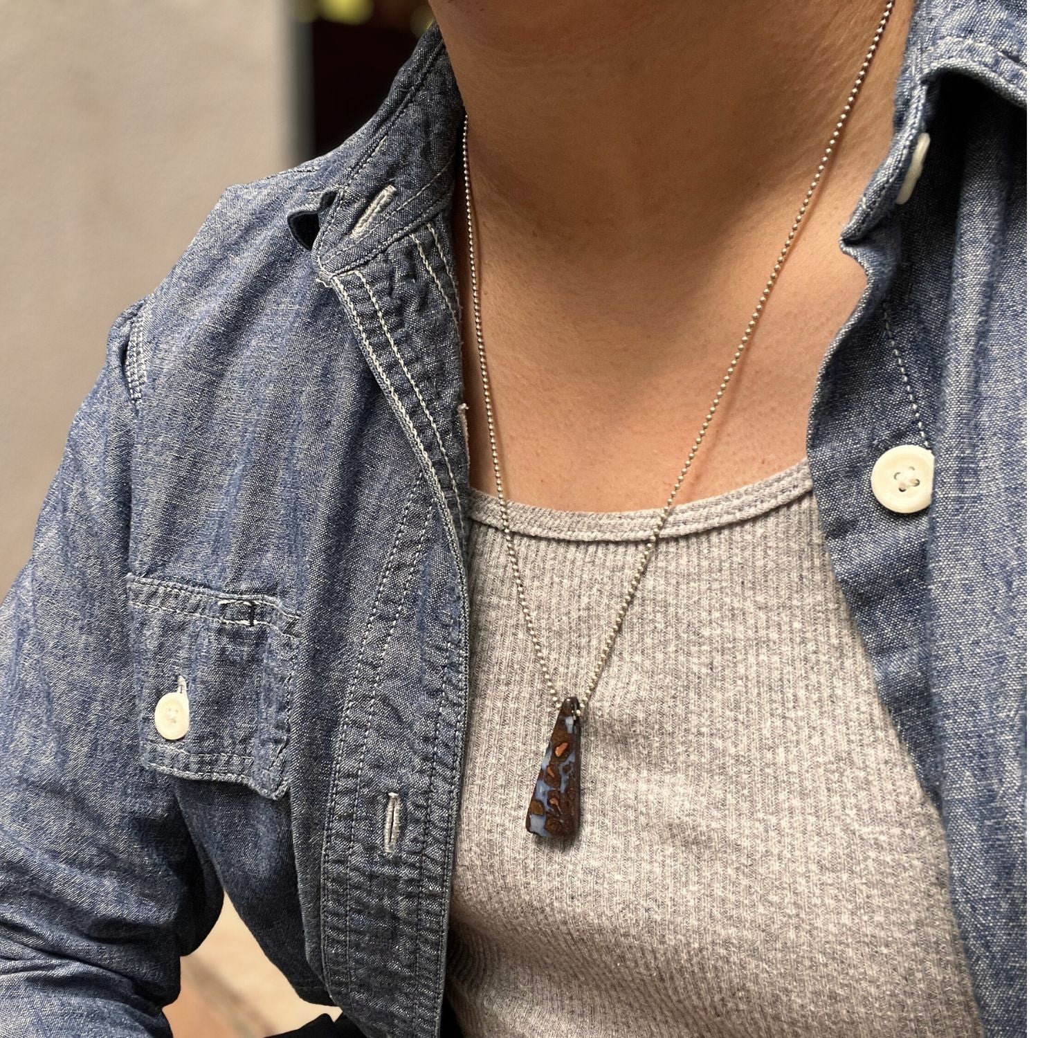The Down Under Australian Boulder Opal Sterling Necklace by JAREDJAMIN Jewelry Online features a triangular marbled purple and brown opal pendant on a delicate, unclasped silver chain, displayed against a white background.