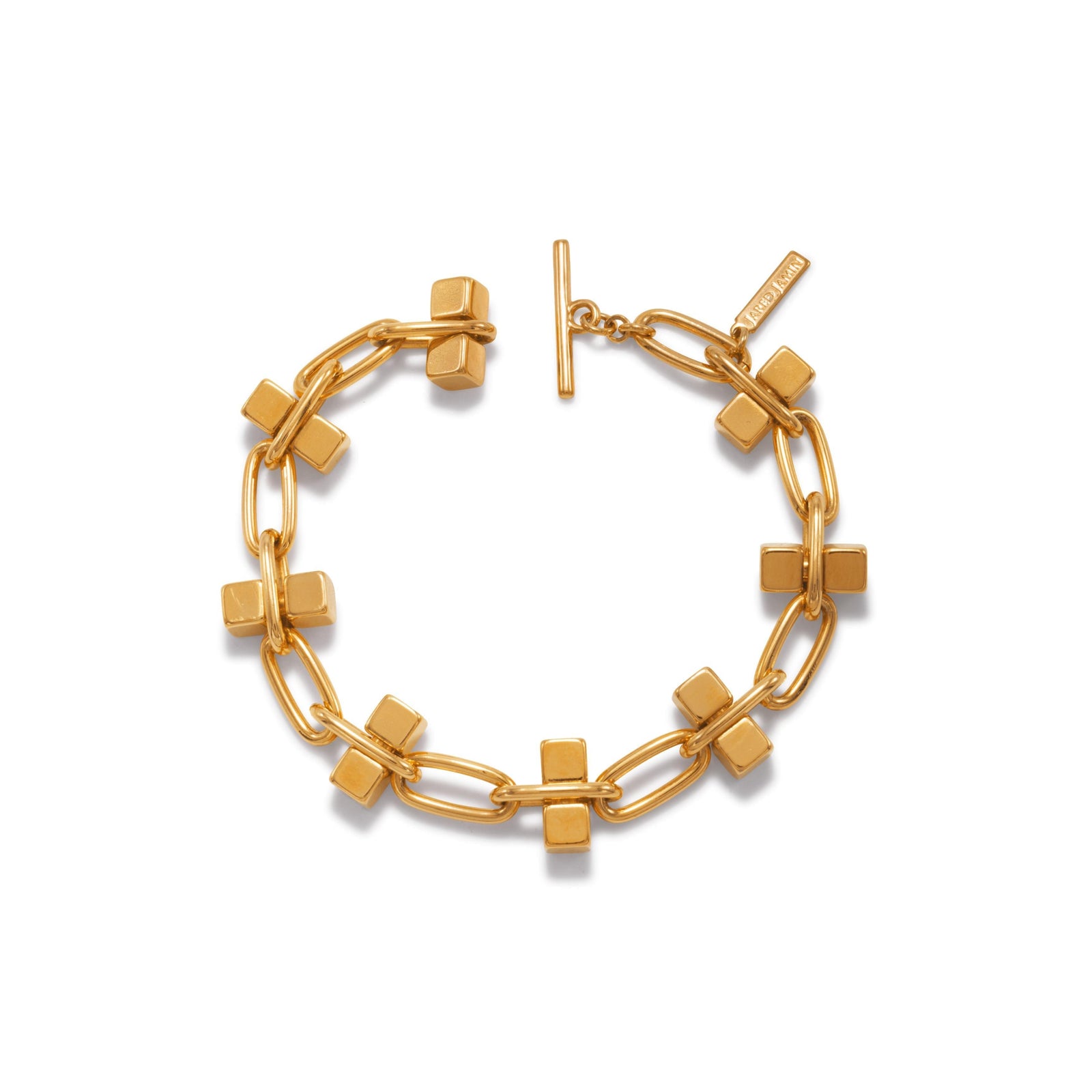 The Blockbuster Gold Chain Bracelet by JAREDJAMIN Jewelry Online features 18K gold plating, elongated oval links, gold cube charms, a toggle clasp, and a rectangular "MSGM" engraved tag for an elegant look.