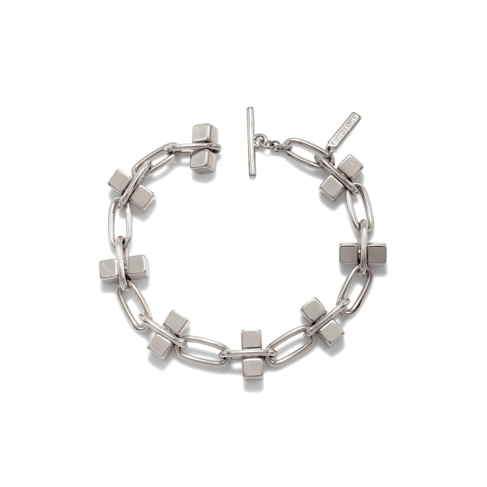 The Blockbuster Silver Chain Bracelet by JAREDJAMIN Jewelry Online features a modern geometric design with large oval links, square charms, a sleek toggle clasp, and an engraved tag, all in a white bronze plated finish.