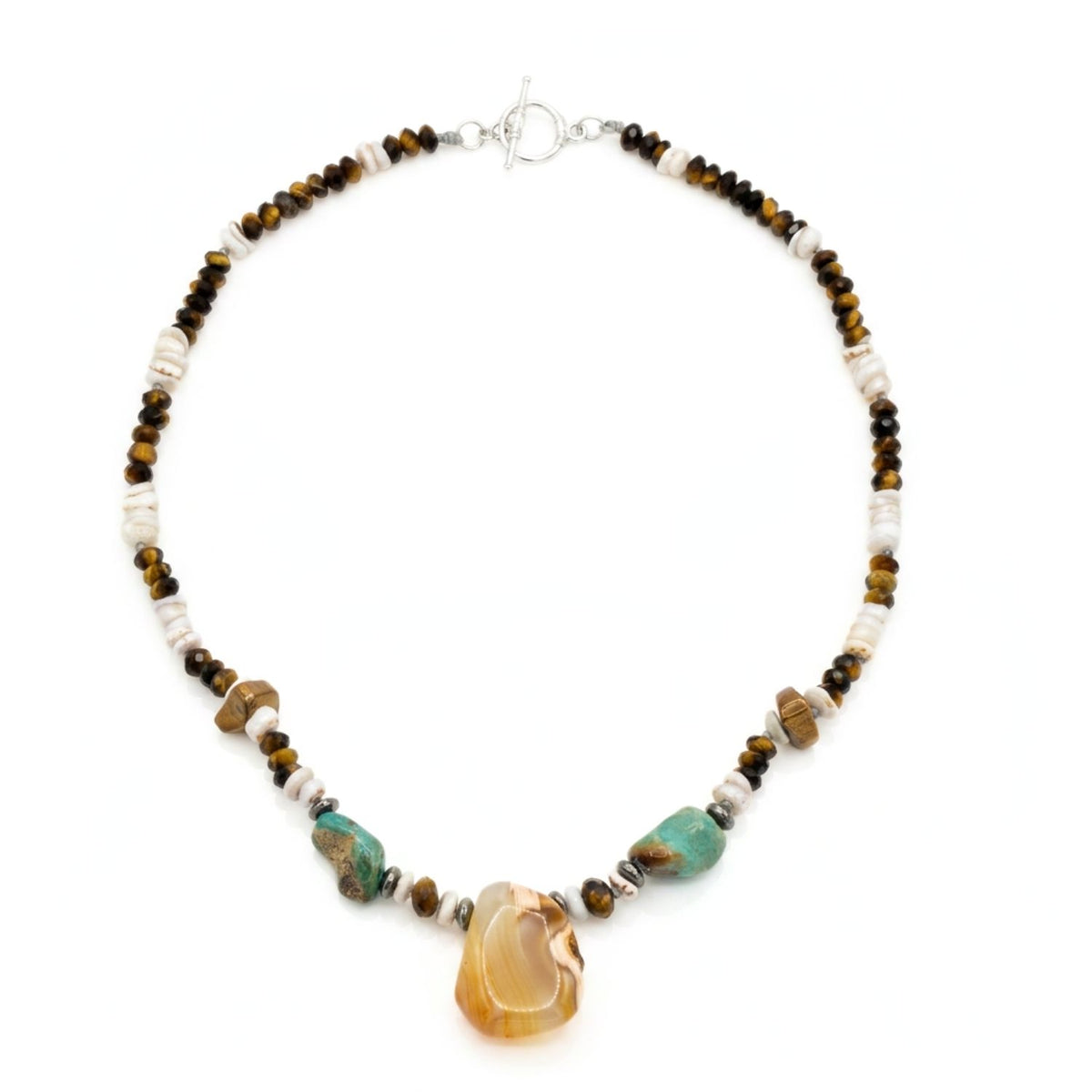 High-resolution studio product shot of the JAREDJAMIN men's Badlands necklace against a clean white backdrop, detailing the faceted tiger's eye rondelles, white shell discs, turquoise beads, and the polished irregular agate pendant with its sterling silver toggle clasp.