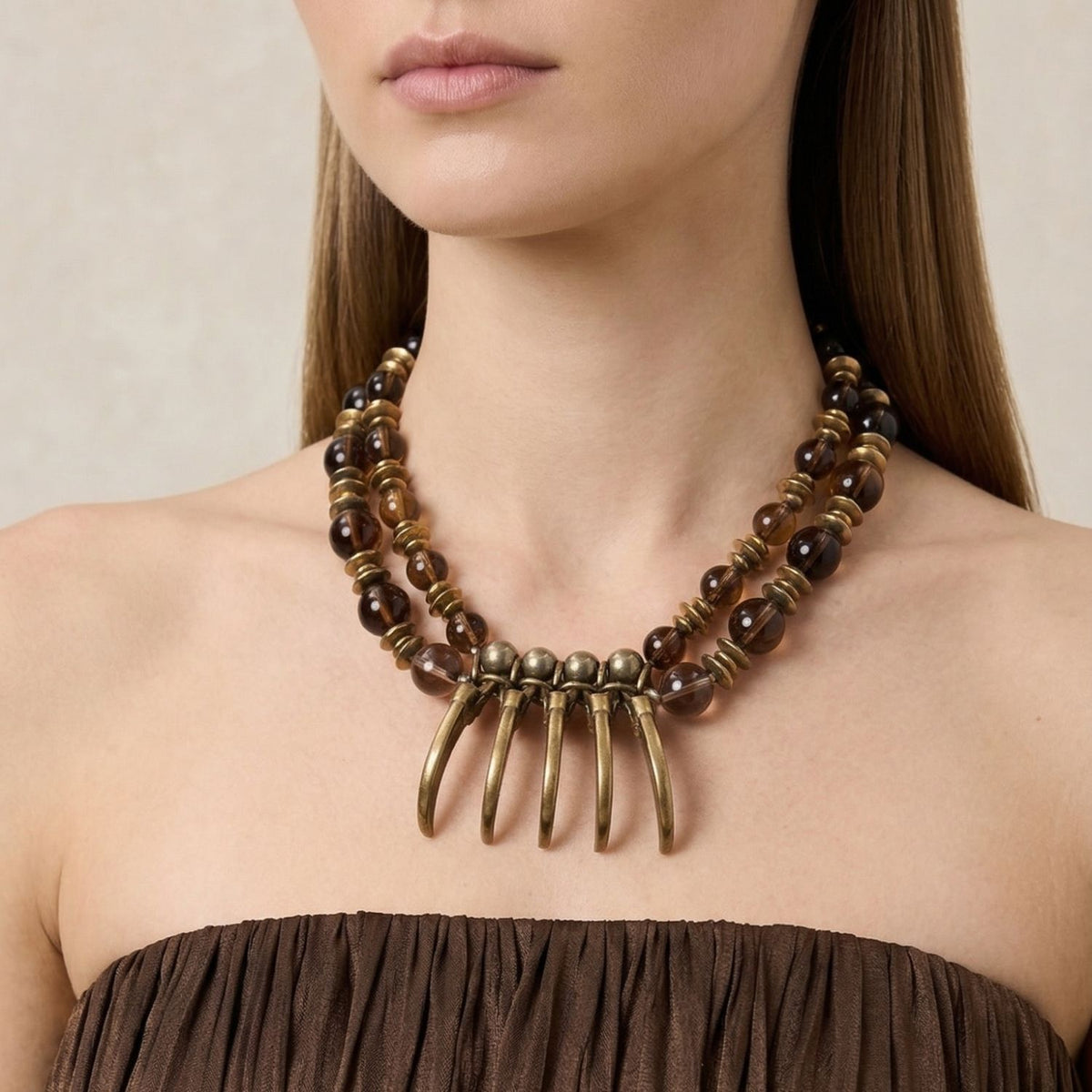 Los Valkyrie piedra preciosa collar de JAREDJAMIN Joyería Online showcases amber, oro beads, brass pendants, y smoky quartz pyrite. Artisanal craftsmanship small-batch/West Hollywood, sustainable de lujo, signature brushed textures. Woman’s neck visible.