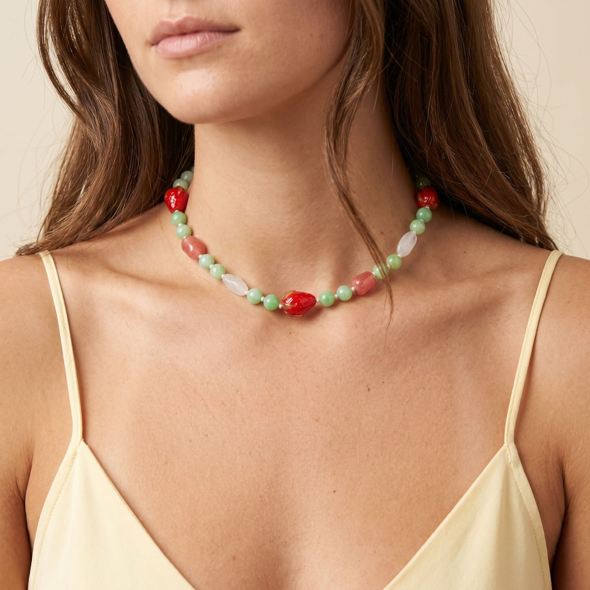 Close-up shot of a model wearing the converted 16-inch Berry Crush gemstone strand as a high-fashion choker necklace, showcasing its versatility, color composition, and coastal luxury aesthetic against a cream top.