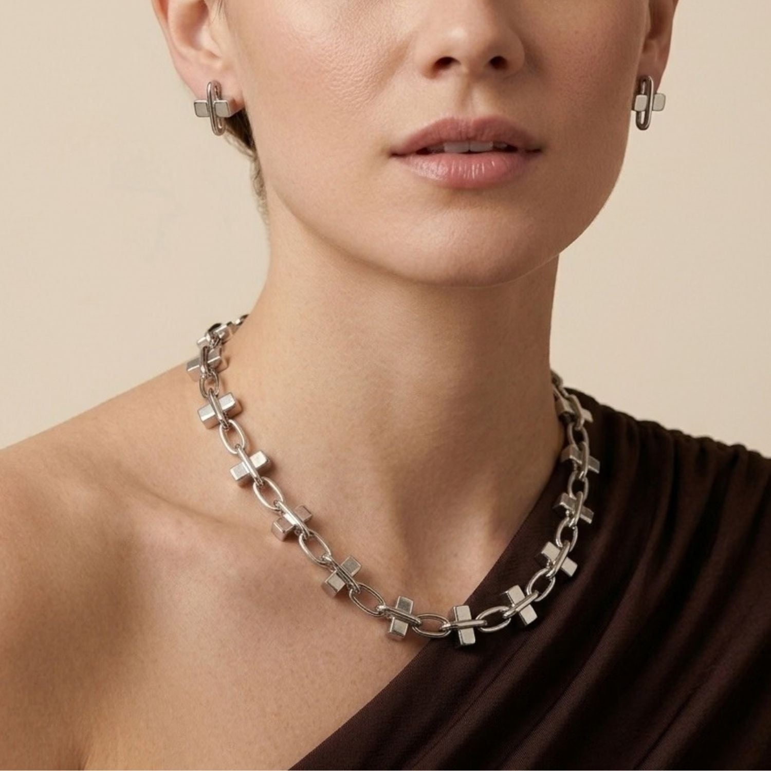 Overhead view of the JAREDJAMIN Silver Blockbuster Stud Post Earrings arranged on a white surface, showcasing the bright silver-plated finish and the unique intersection of the rigid cube and floating oval link.