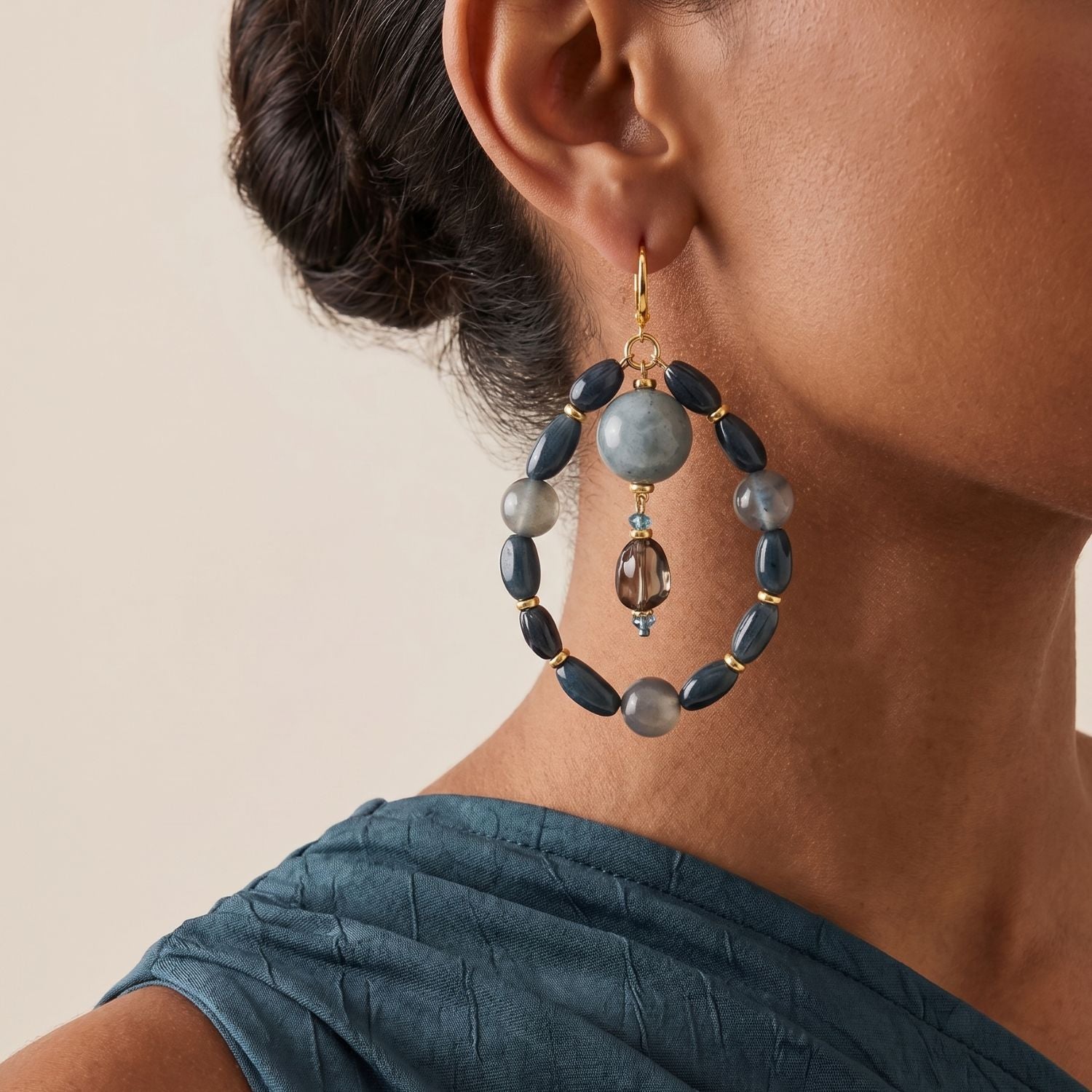 High-resolution studio product shot of the JAREDJAMIN Blue Bean Hoop Earrings against a white backdrop, showcasing the gold-plated lever back posts, the outer navy and blue lace agate beaded loops, and the central hanging smoky crystal drop pendants.