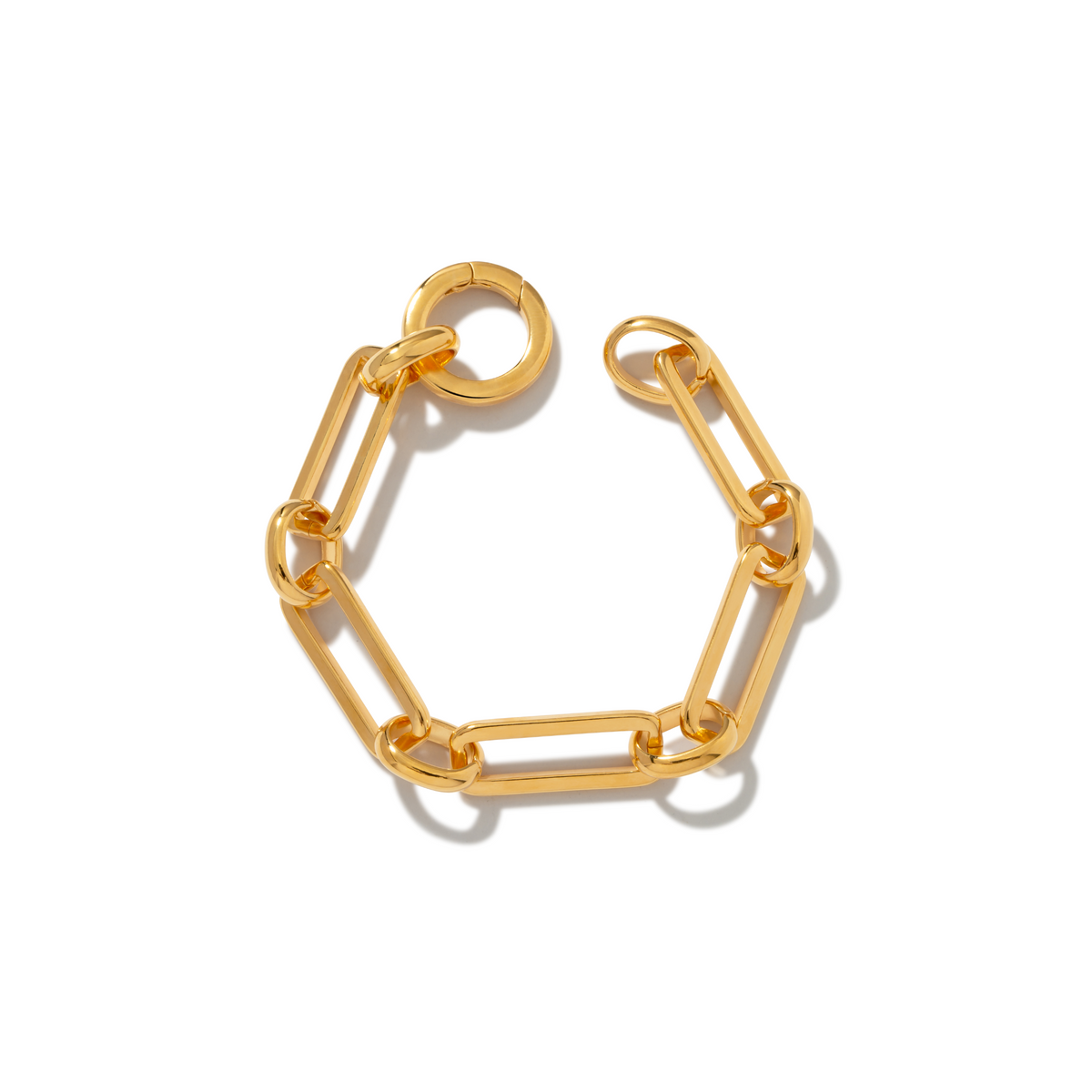 The Gold Bravura Link Chain Bracelet by JAREDJAMIN Jewelry Online features large, elongated rectangular links and a detachable clicker clasp, arranged in a circle on a white background with a shiny, polished finish for elegant style.