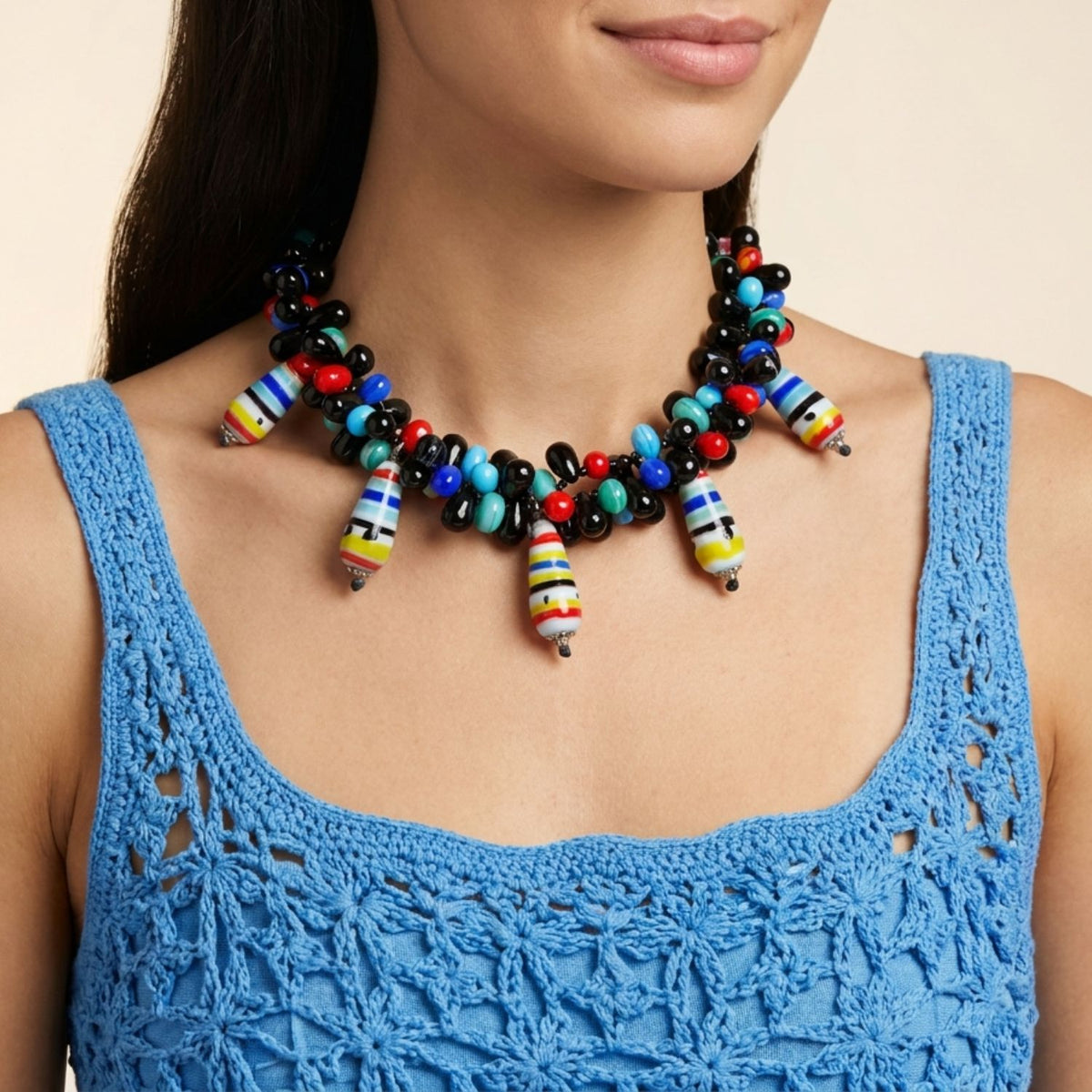 Front portrait of a female model wearing a blue crochet top and the 16-inch Candy Dandy Necklace, demonstrating how the colorful vintage glass and agate statement clusters rest vibrantly along the collarbone.