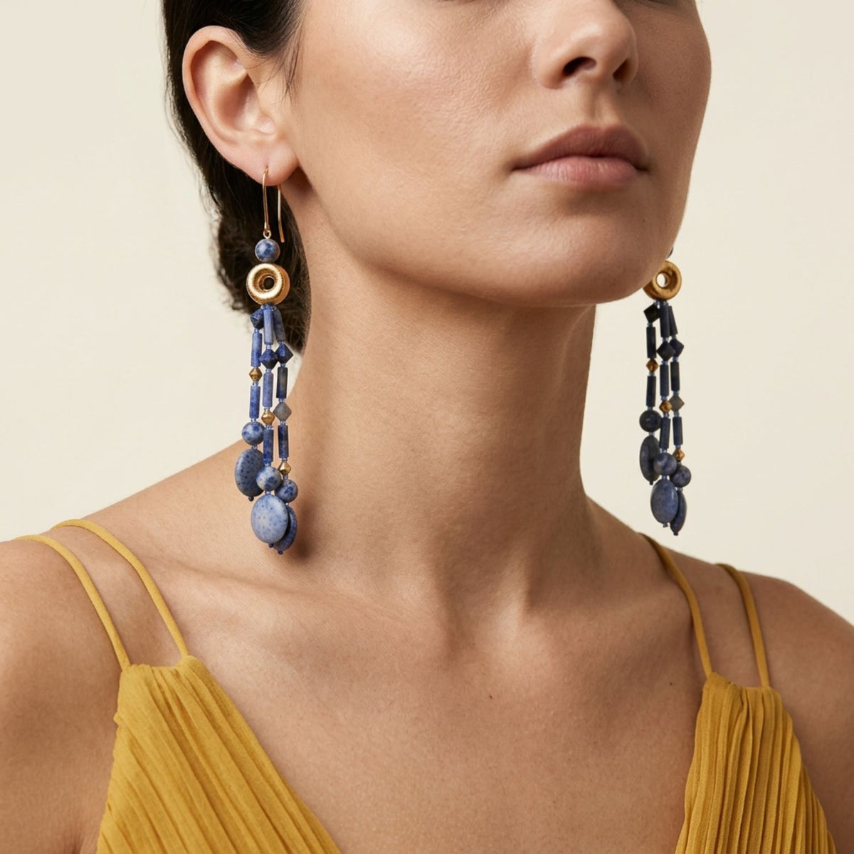 Front portrait view of a model wearing the 5.25-inch Celeste Sodalite and Coral Tassel Earrings, demonstrating their shoulder-grazing length and deep blue color blocking paired with a textured yellow top.