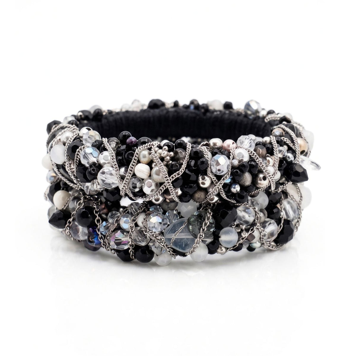 High-resolution, top-down flat lay photography shot with a Canon EOS 5D Mark IV macro lens, featuring the JAREDJAMIN Cocktail Clappers Bangle Set stacked on a white background to highlight the dense black, white, and gunmetal bead embroidery and woven silver chain.
