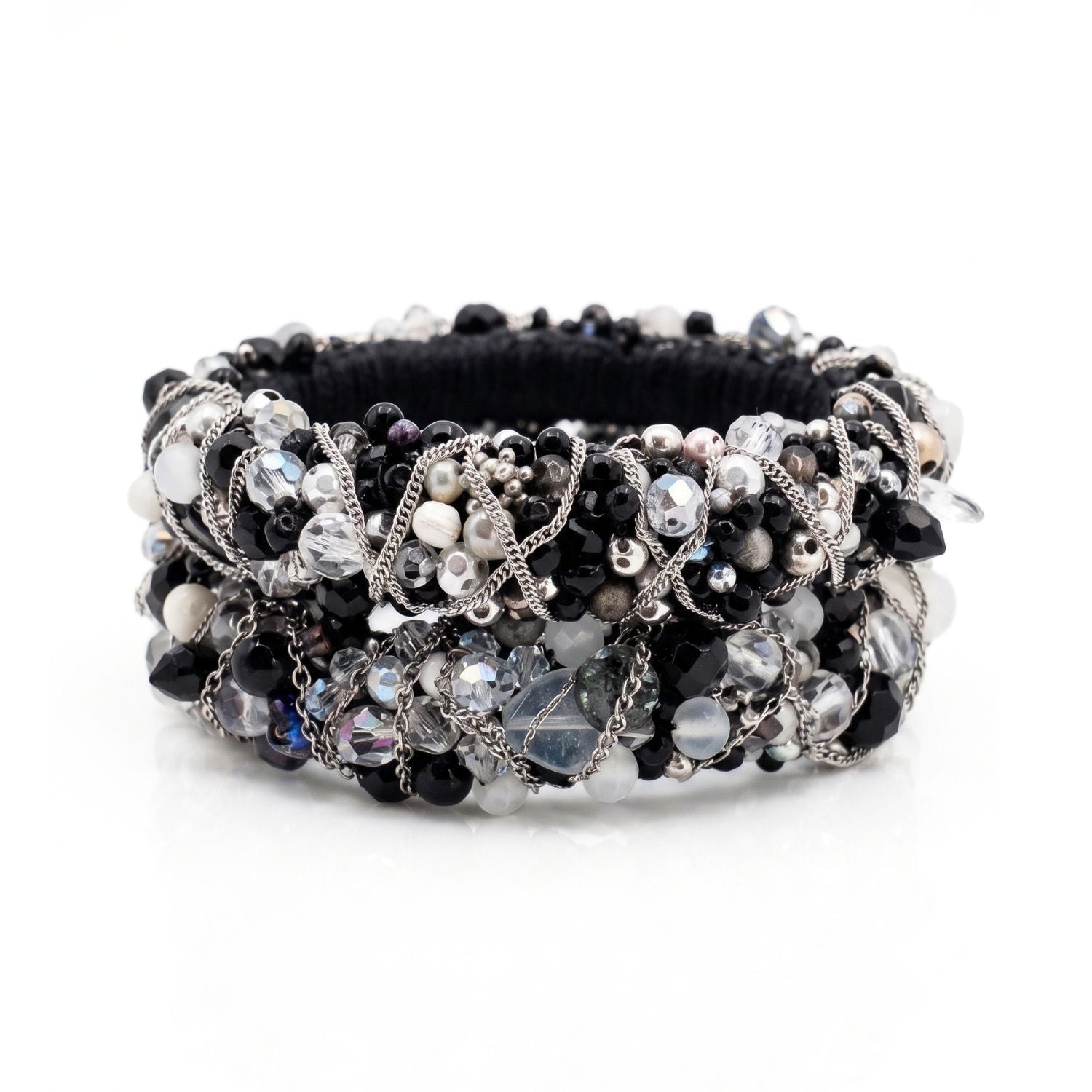 High-resolution, top-down flat lay photography shot with a Canon EOS 5D Mark IV macro lens, featuring the JAREDJAMIN Cocktail Clappers Bangle Set stacked on a white background to highlight the dense black, white, and gunmetal bead embroidery and woven silver chain.