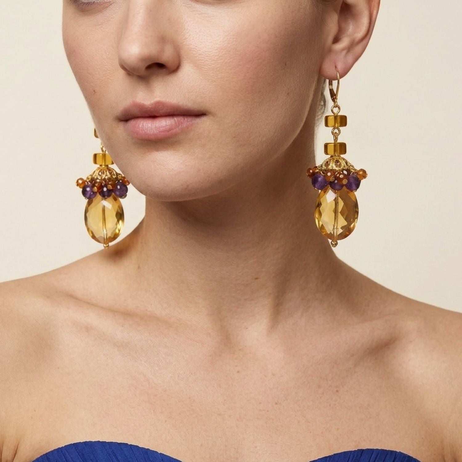 High-resolution studio product shot of the JAREDJAMIN Copacabana Dangle Earrings, showcasing the gold-finished lever-backs, stacked circular amber glass beads, and the large faceted amber crystals adorned with clustered amethyst and carnelian charms against a white backdrop.