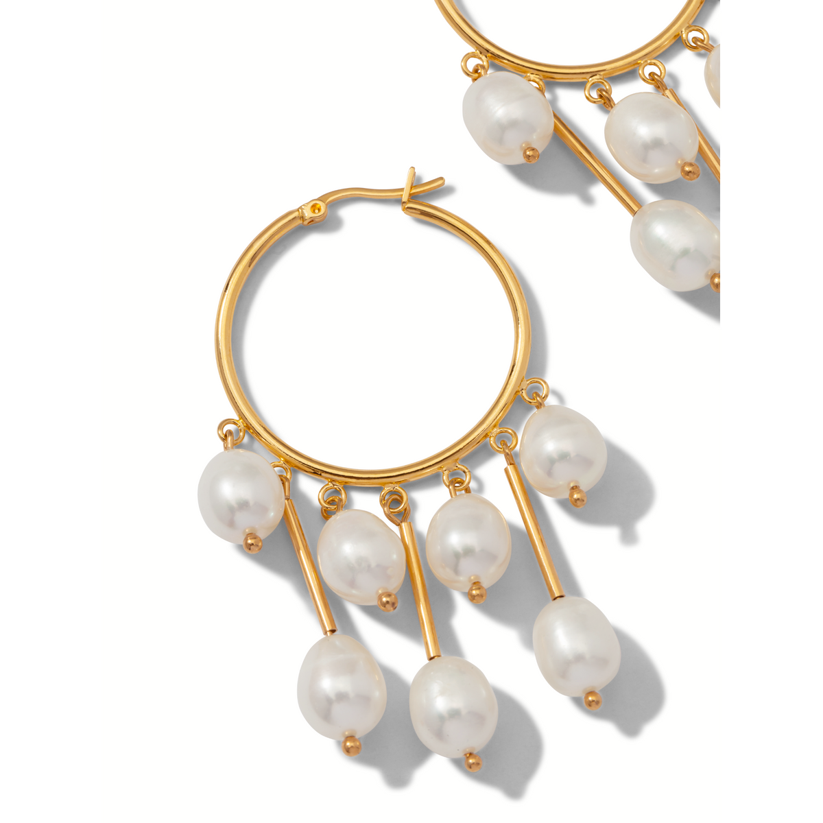 Les Daniela Dangle créole perle boucles d'oreilles par JAREDJAMIN Bijoux en Ligne présentent brillant 18K plaqué or créoles avec five oval freshwater perles on short or rods. Un second boucle d'oreille is partially visible against a fond blanc.