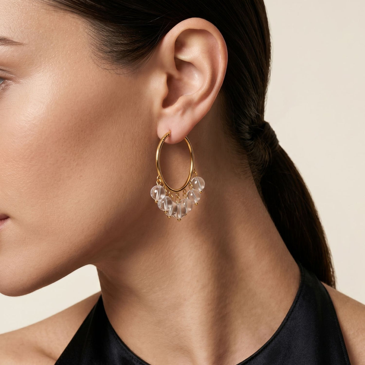 A model wearing the Daniela Clear Quartz Hoops, highlighting the architectural movement and light-refracting quality of the smooth stones.