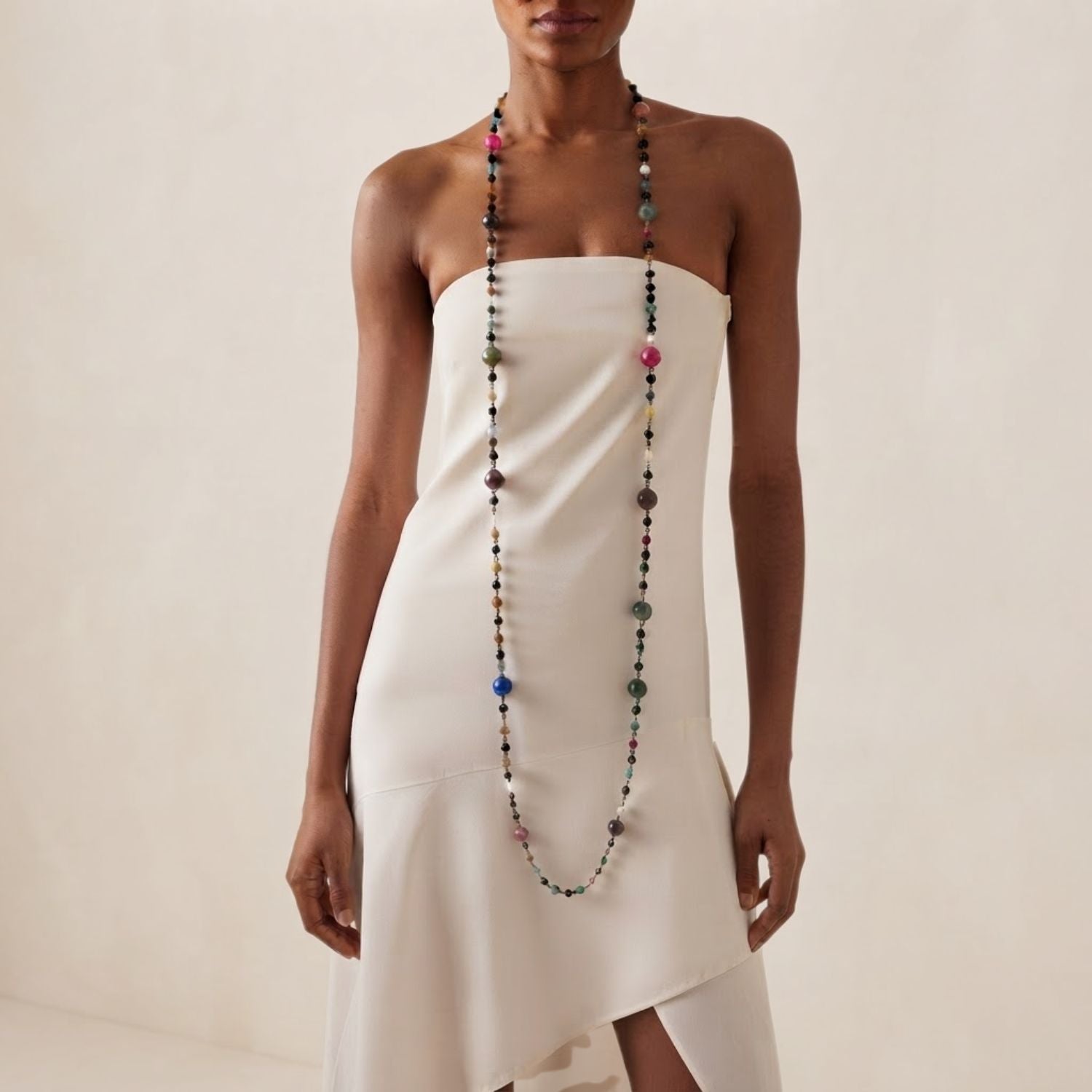 High-resolution studio top shot of the Caelum Cosmic Strand elegantly coiled in multiple circular tiers on a white background, highlighting the contrast between the dark gunmetal wire and the colorful gemstone planet spheres.
