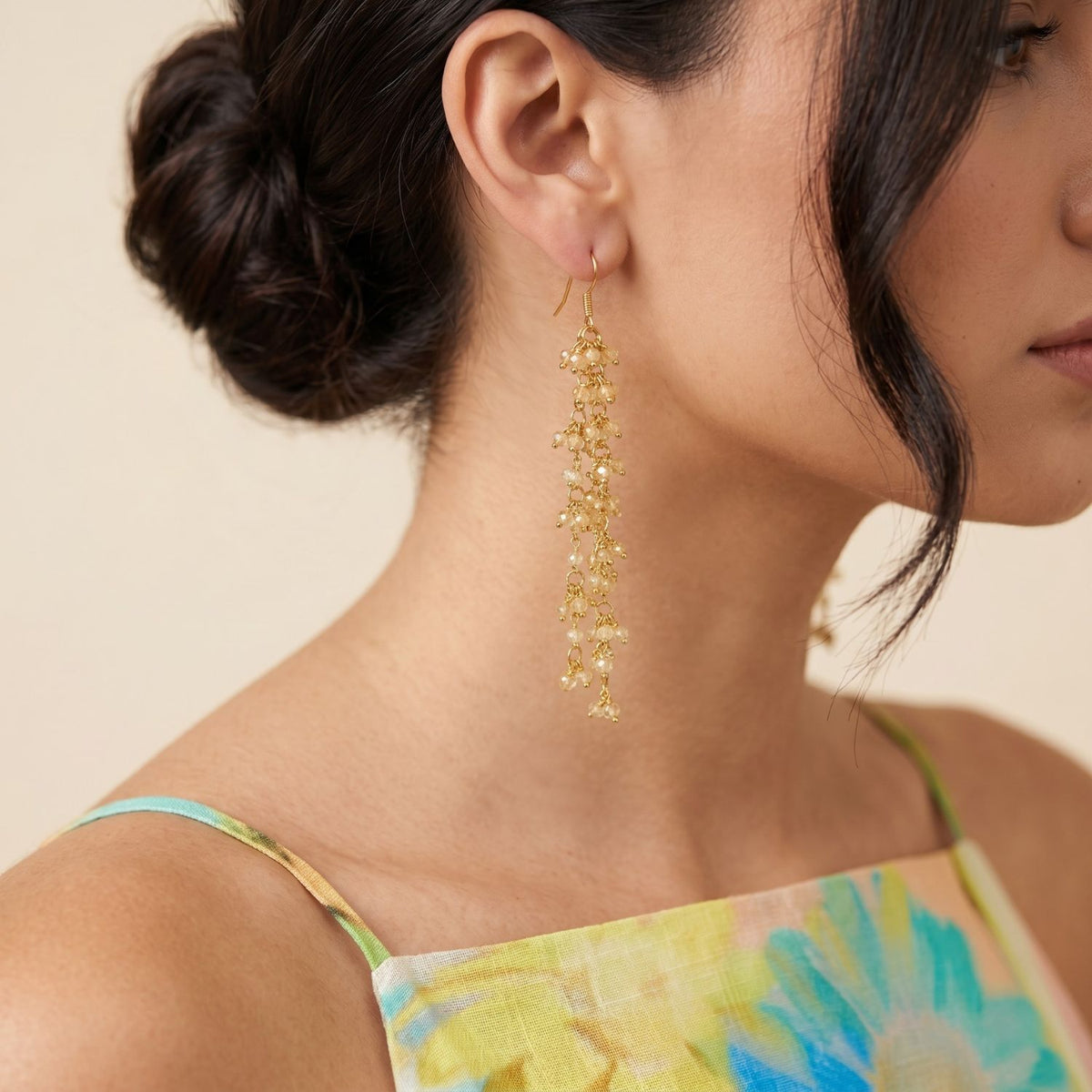 Side profile portrait view of a model wearing the 4-inch Eloise Citrine Cluster Dangle Earrings, demonstrating their delicate floral vine illusion and soft light reflection paired with a green and blue patterned top.