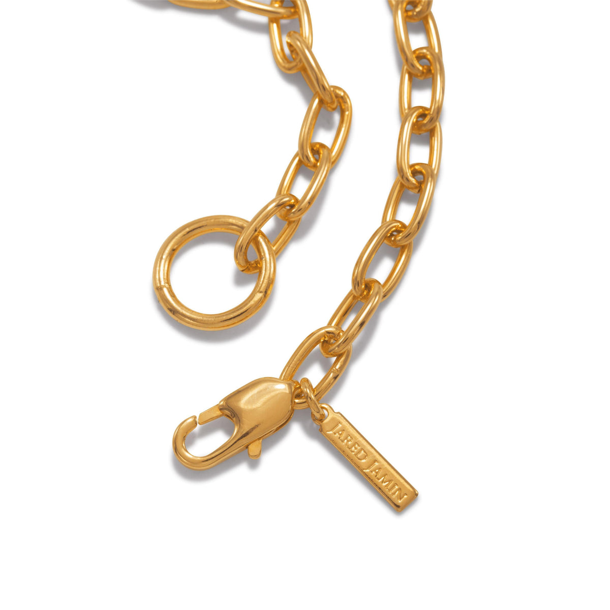 primer plano of the oro cadena Reaction pulsera de JAREDJAMIN Joyería Online, con oval links, a lobster clasp, y an "ARED LAMIN" tag. Its 18K bañado en oro, scratch- y tarnish-resistant finish shines sobre un fondo blanco.