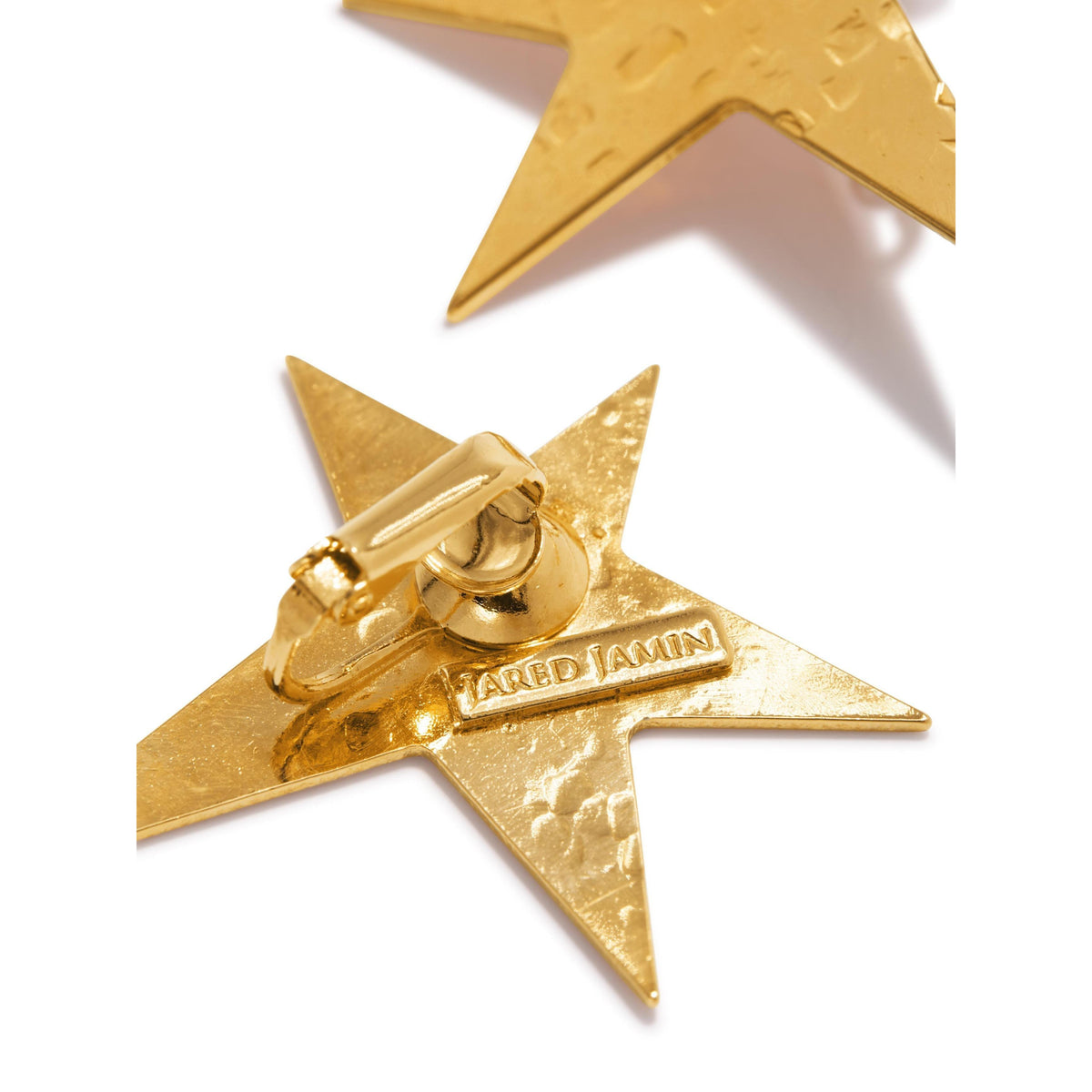 Close-up of Gold Shooting Star Dangle Clip On Earrings by JAREDJAMIN Jewelry Online on a white background. One earring is fully shown with textured detail and engraved branding; the other star appears partially at the top.