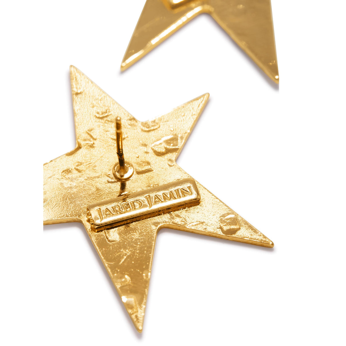 primer plano of a texturizado oro Shooting Star Dangle Post pendiente de JAREDJAMIN Joyería Online, con an 18K oro star y a rectangular plaque engraved con "JARED JAMIN." Another star pendiente appears blurred in the background.