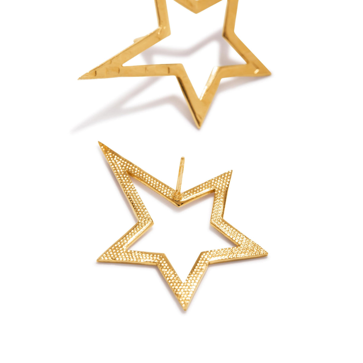 Two or Shooting Star Dust puce Post boucles d'oreilles Sm par JAREDJAMIN Bijoux en Ligne are montré sur a fond blanc—one flat, displaying its dotted texture, et the other angled upward. Both présentent an open star design avec a brilliant metallic finish.