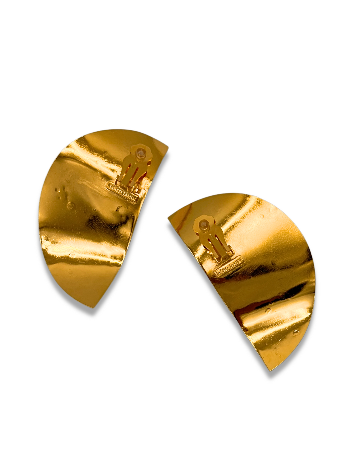 Two golden, semi-circular halves of a broken chocolate bar resemble architectural pieces with embossed patterns. Each shiny piece suggests a former whole, much like the Geo Twist Earrings by JAREDJAMIN Jewelry Online. The background is plain white.