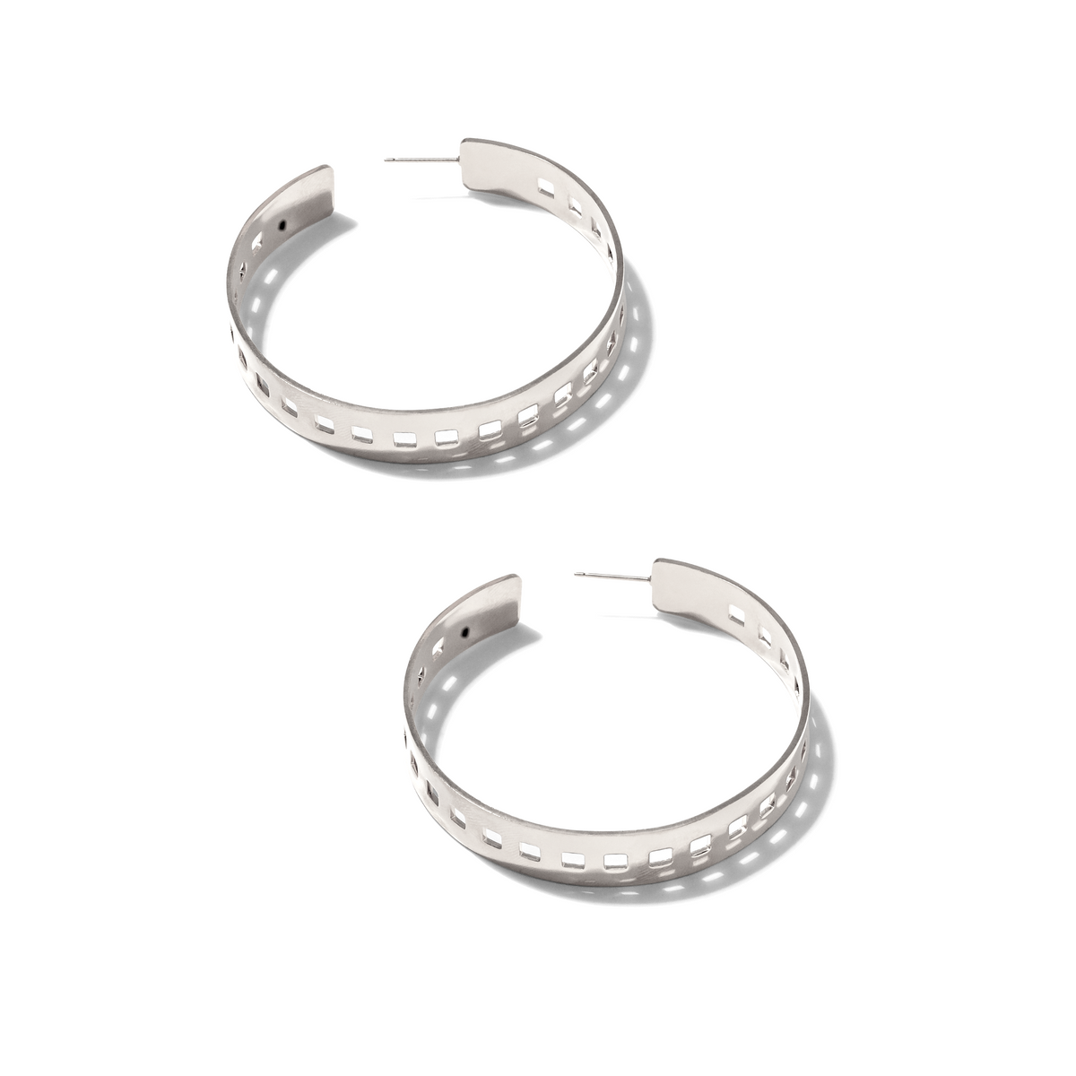 Les 'Girls On Film' créole Post boucles d'oreilles par JAREDJAMIN Bijoux en Ligne are argent, semi-circular créoles avec rectangular cut-outs along the band, montré sur a fond blanc avec soft shadows et straight post fastenings.