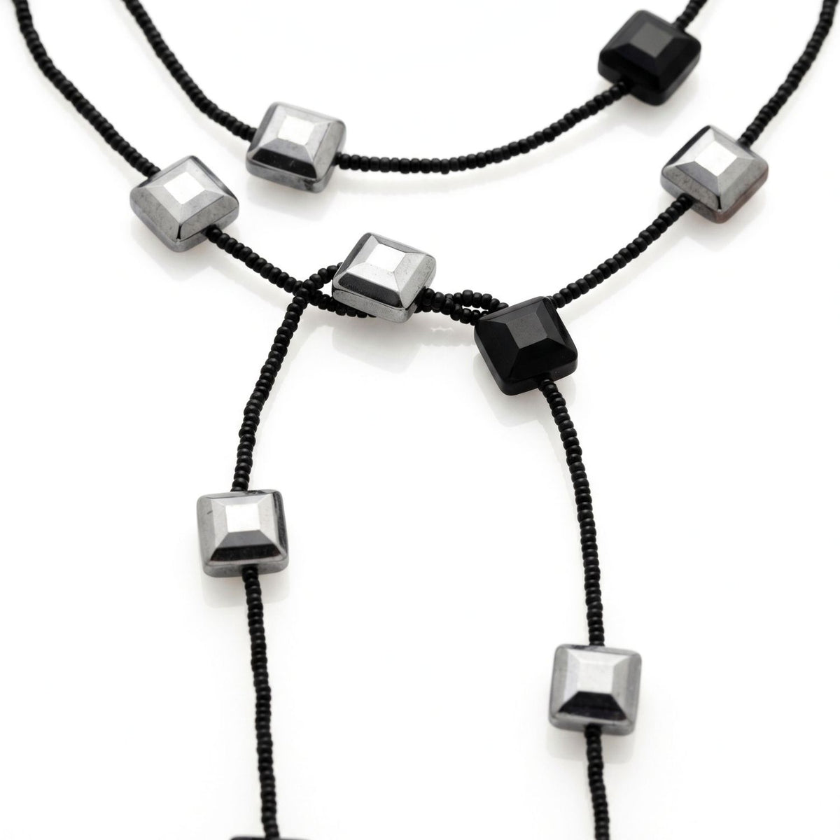 Close-up detail of the Juno lariat: faceted black and mirror-silver square crystals threaded on strands of black glass seed beads.