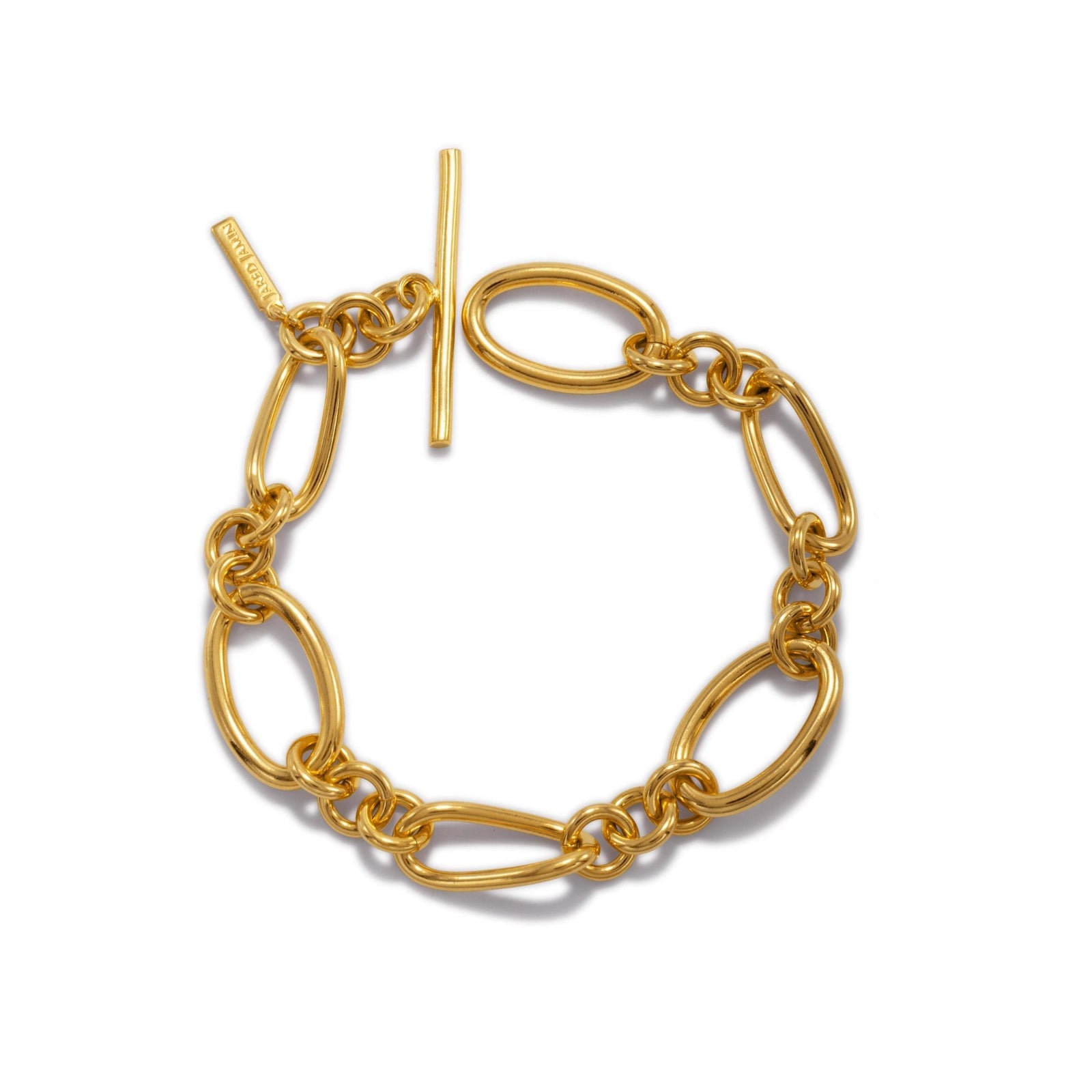The Gold Ophelia Chain Toggle Bracelet by JAREDJAMIN Jewelry Online features large, oval 18K gold-plated links, a toggle clasp with an engraved tag, and a shiny finish that highlights its polished, elegant design.