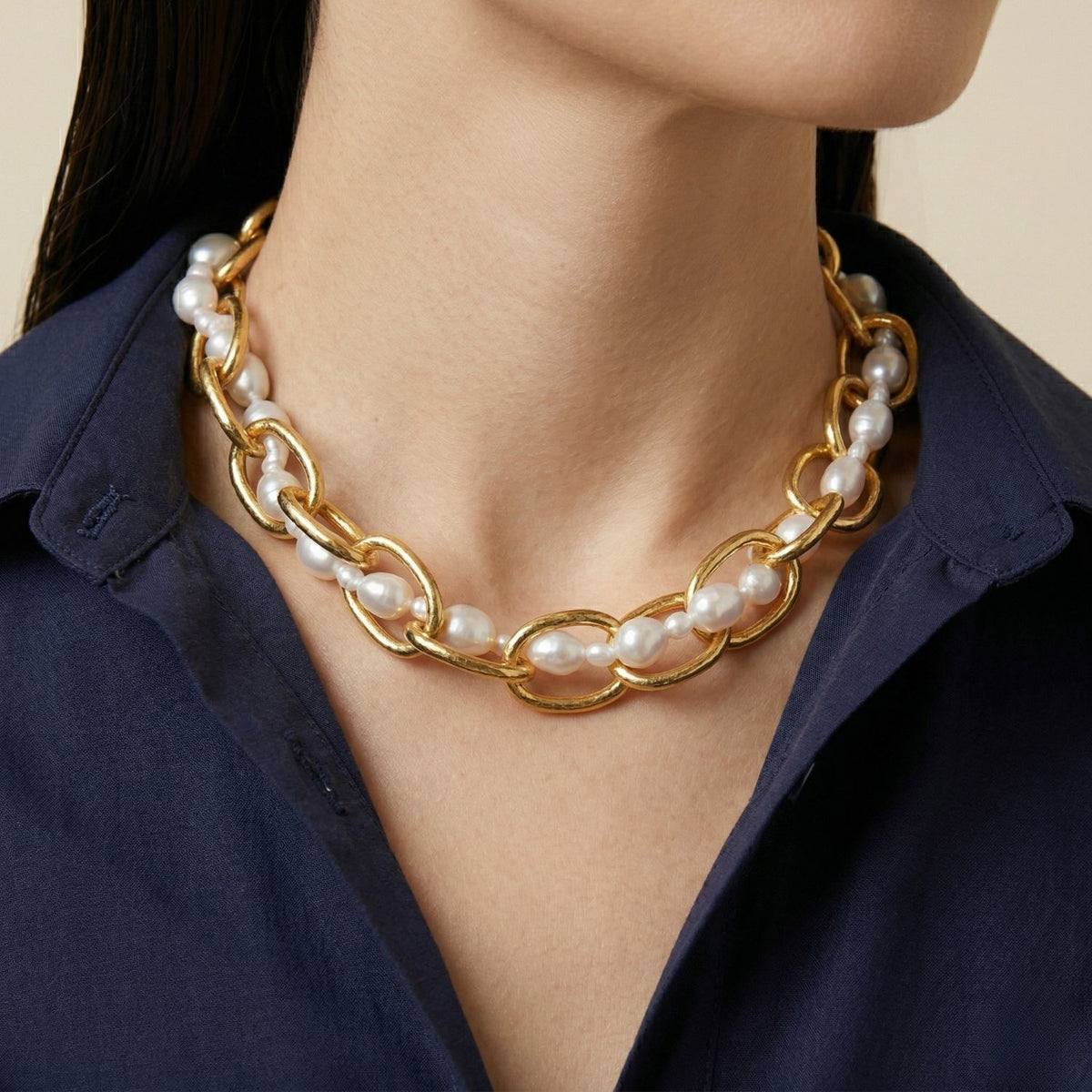 A woman wears the Gold Billie and Pearl Chain Necklace—hand-assembled in our West Hollywood studio—over a dark blue collared shirt. Interlinked gold and pearl strands punctuate her collarbone. Small-batch, eco-conscious. Style Note: Polishes tailoring or silk slip dresses.