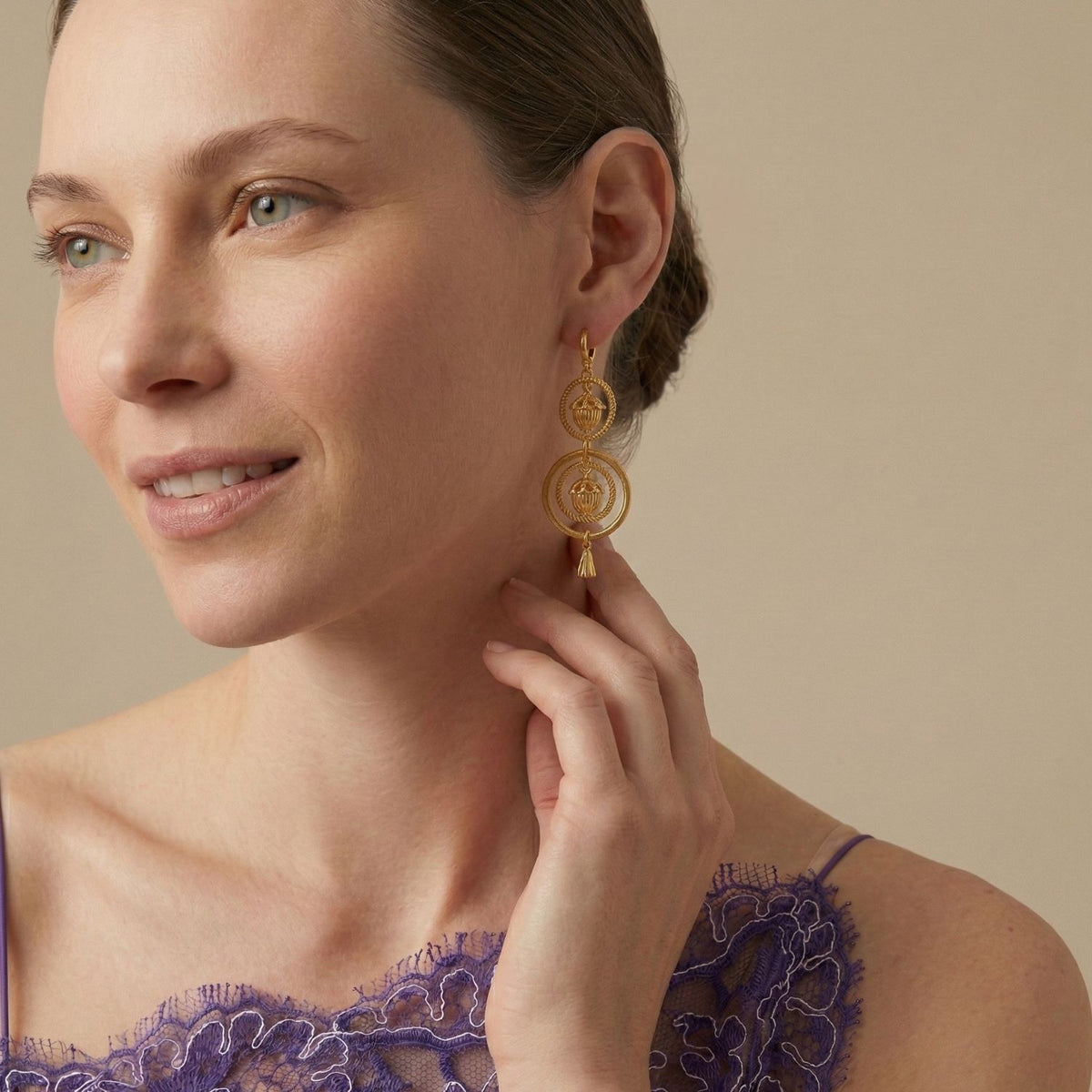 Gold Bollywood Dangle Leverback Earrings by JAREDJAMIN Jewelry Online, crafted with a brushed finish and artisanal small-batch techniques in West Hollywood. Sustainable luxury, low carbon footprint. Model touches one earring; background is neutral beige.