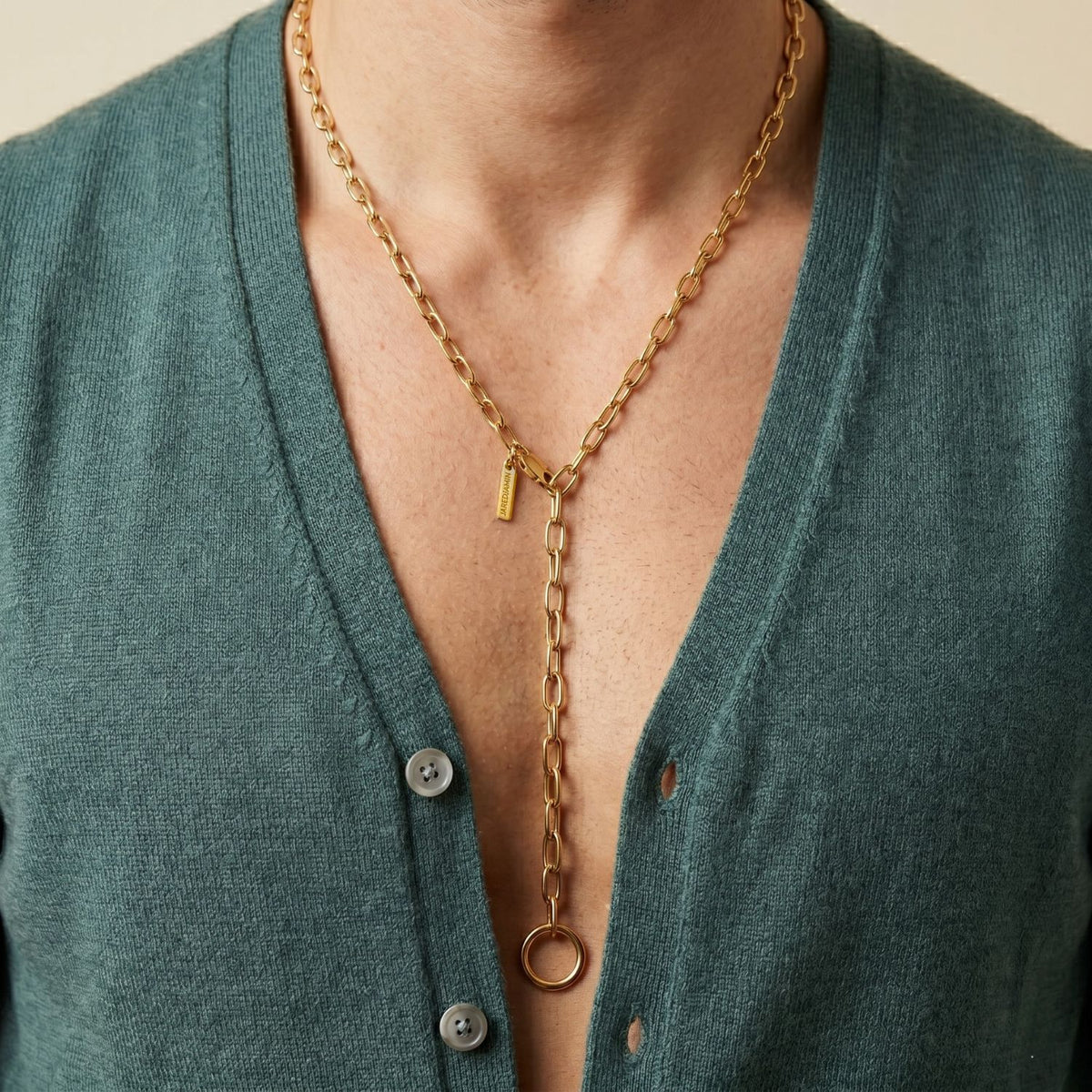 A person in a deep teal cardigan with gray buttons punctuates their look with the Gold Chain Reaction Necklace—18k gold plated, hand-assembled in our West Hollywood studio. Crafted in small, eco-conscious batches. Style Note: refracts light from day layers to evening silk.