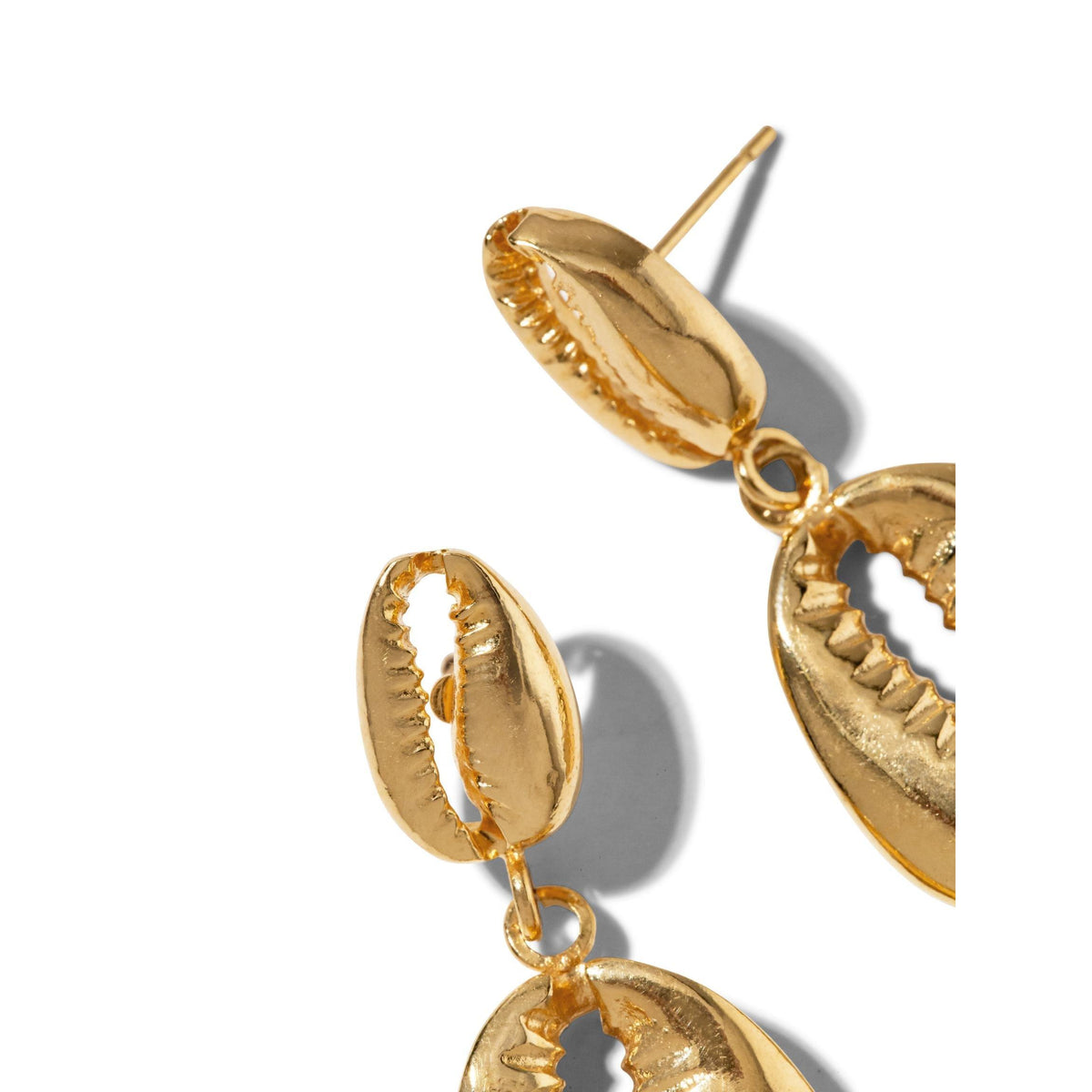 gros plan of JAREDJAMIN Bijoux en Ligne’s or Cowrie pendante boucles d'oreilles, inspiré par cowrie shells avec texturé edges et a glossy finish. Overlapping shell shapes cast soft shadows on white, evoking Summer Shallows.