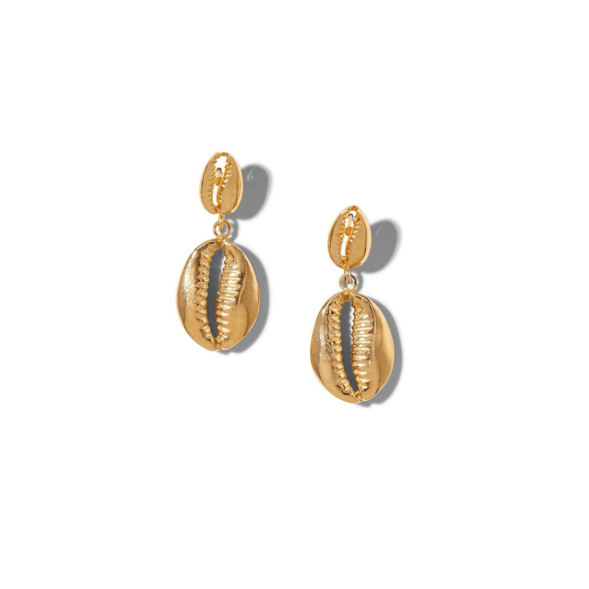 Les or Cowrie pendante boucles d'oreilles de JAREDJAMIN Bijoux en Ligne présentent 18K or plating, a brillant metallic finish, et a distinctive double cowrie shell design that casts subtle shadows sur un fond blanc.