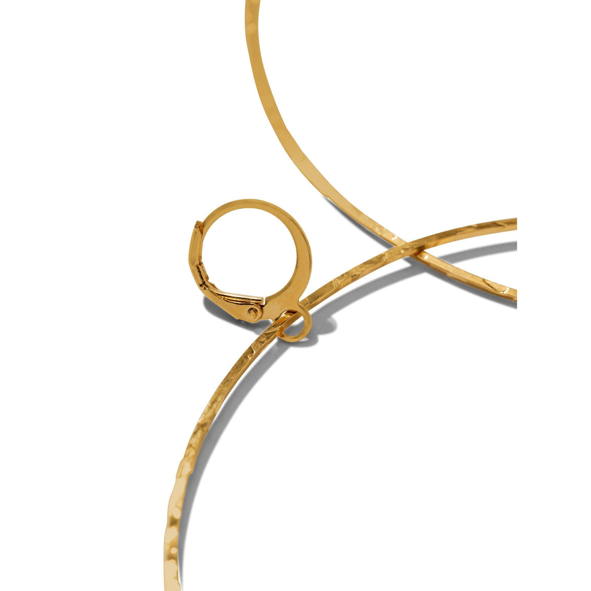 primer plano of JAREDJAMIN Joyería Online’s oro Halo texturizado aro pendientes, con a hammered finish y lever back clasp, shown partially against a fondo blanco to highlight their metallic shine y unique texture.
