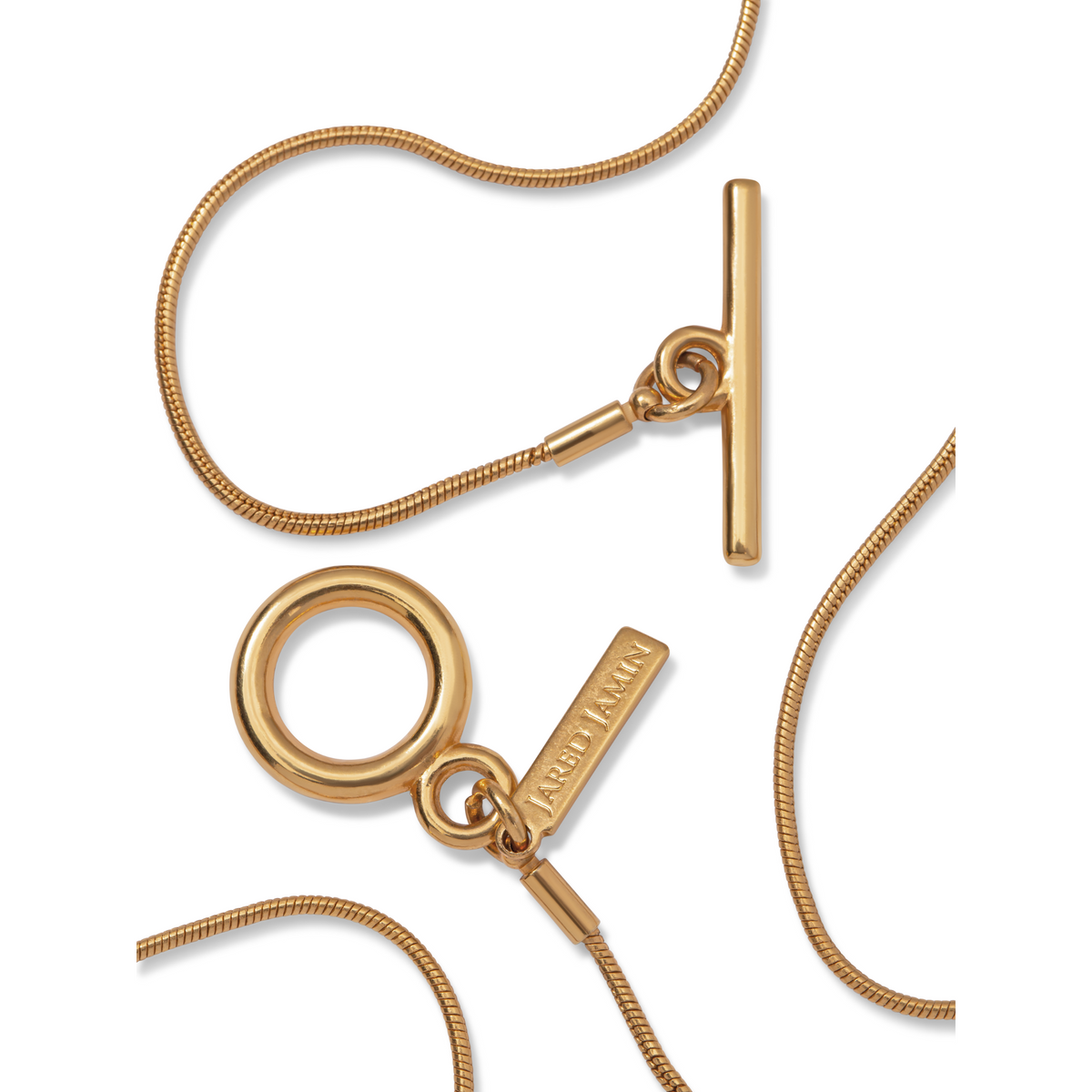 primer plano of the Heavenly aro Oval colgante collar de JAREDJAMIN Joyería Online, con an 18K oro-tone snake link cadena con toggle clasp, oval colgante, y branded tag, elegantly arranged sobre un fondo blanco.