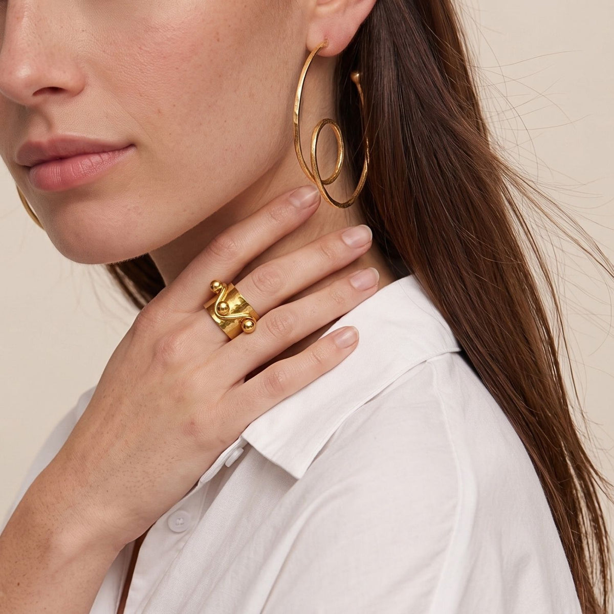 Gold Loop-De-Loop Hoop Post Earrings, model wearing yellow gold hoop earrings of interlinked loop-de-loop hoops, close-up.