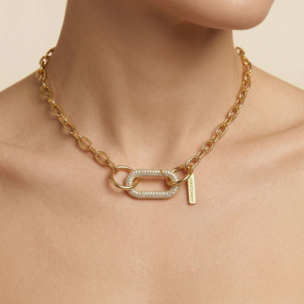 A close-up captures the JAREDJAMIN Gold Oval Pavé Clicker Clasp necklace—weighty, hand-assembled links from our West Hollywood studio, an oval pavé focal point, and a precise clasp. Made small-batch with eco intent. Style Note: punctuates blazers or slip dresses.