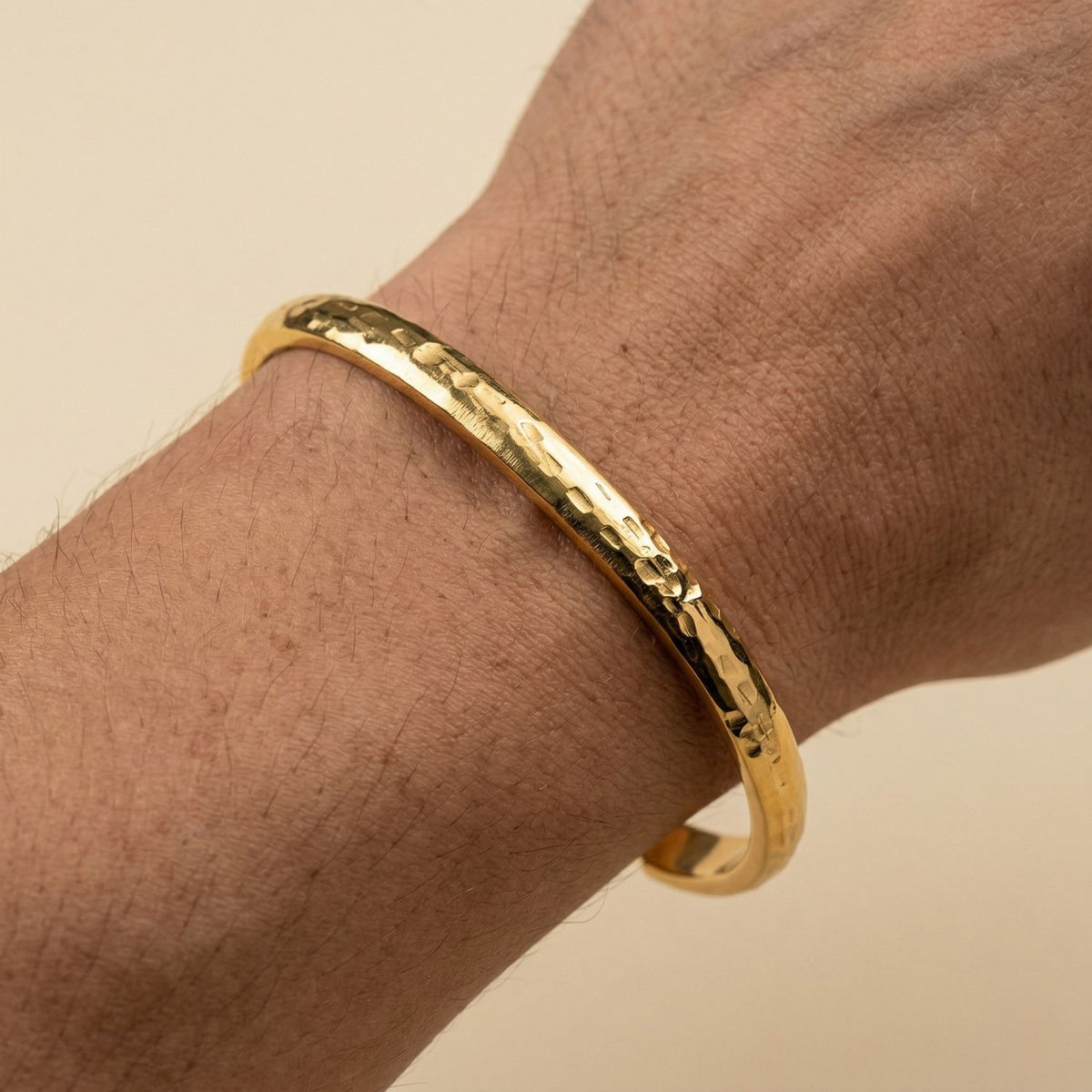A close-up of a light to medium skin wrist punctuates the scene, capturing the Gold Parker Textured Cuff—sculpted and hand-assembled in our West Hollywood studio. Responsibly crafted in small batches. Style Note: shifts easily from tailored suiting to silk slip dresses.