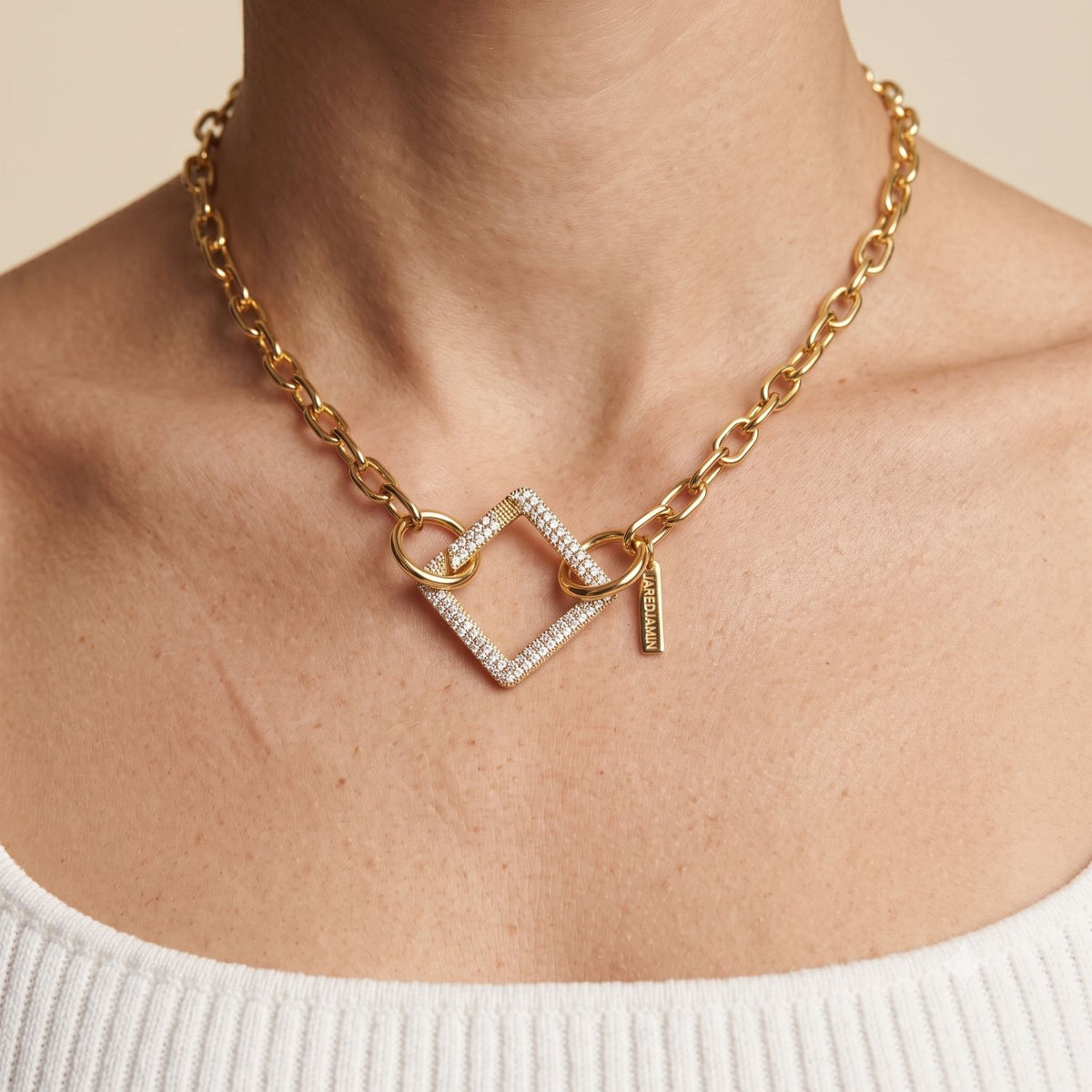 Front view portrait of a model wearing the 18k gold pavé square clicker clasp styled as a central diamond-oriented pendant on a gold link chain necklace.