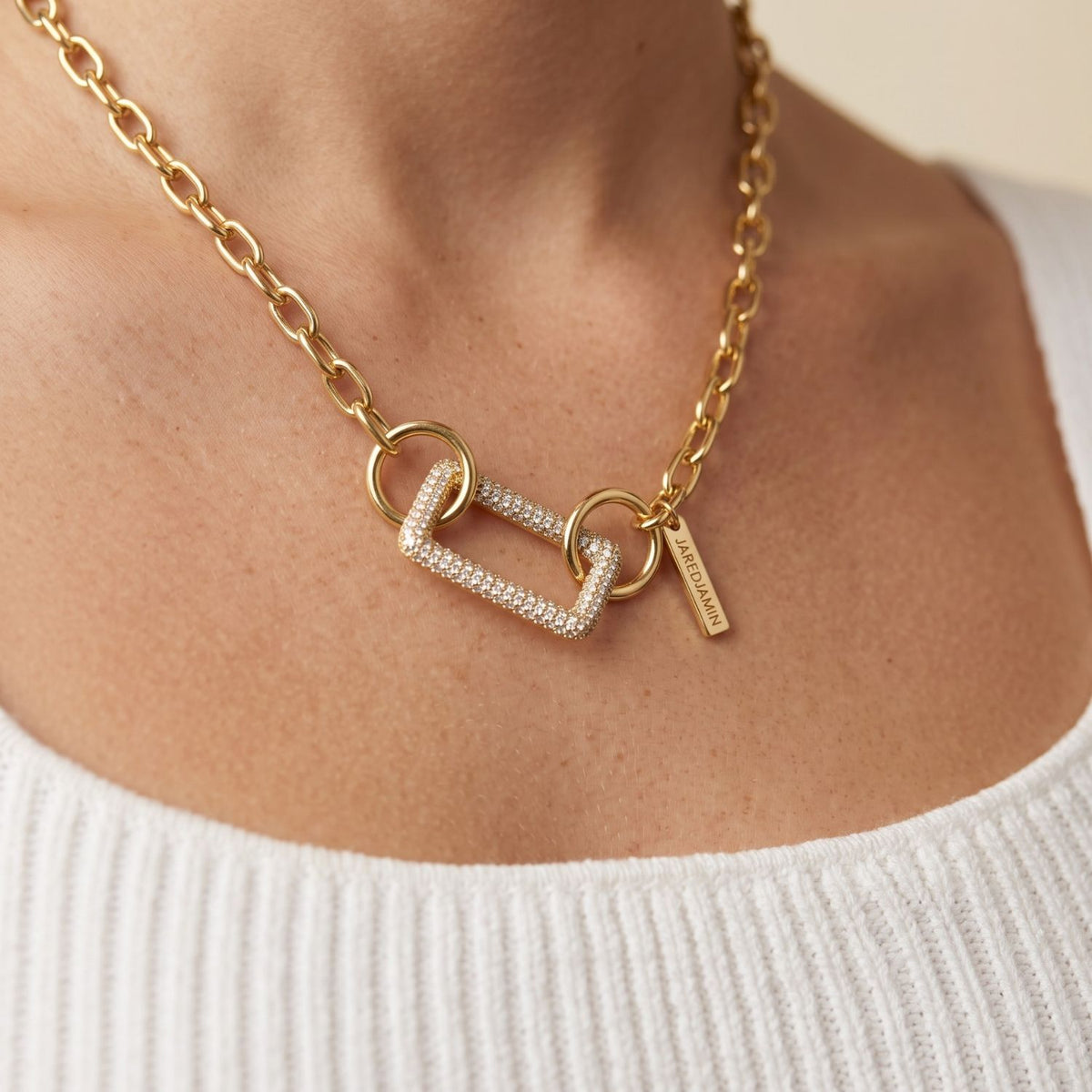 Front view portrait of a model wearing the 18k gold pavé rectangular clicker clasp styled as a central pendant connector on a chunky gold link chain.