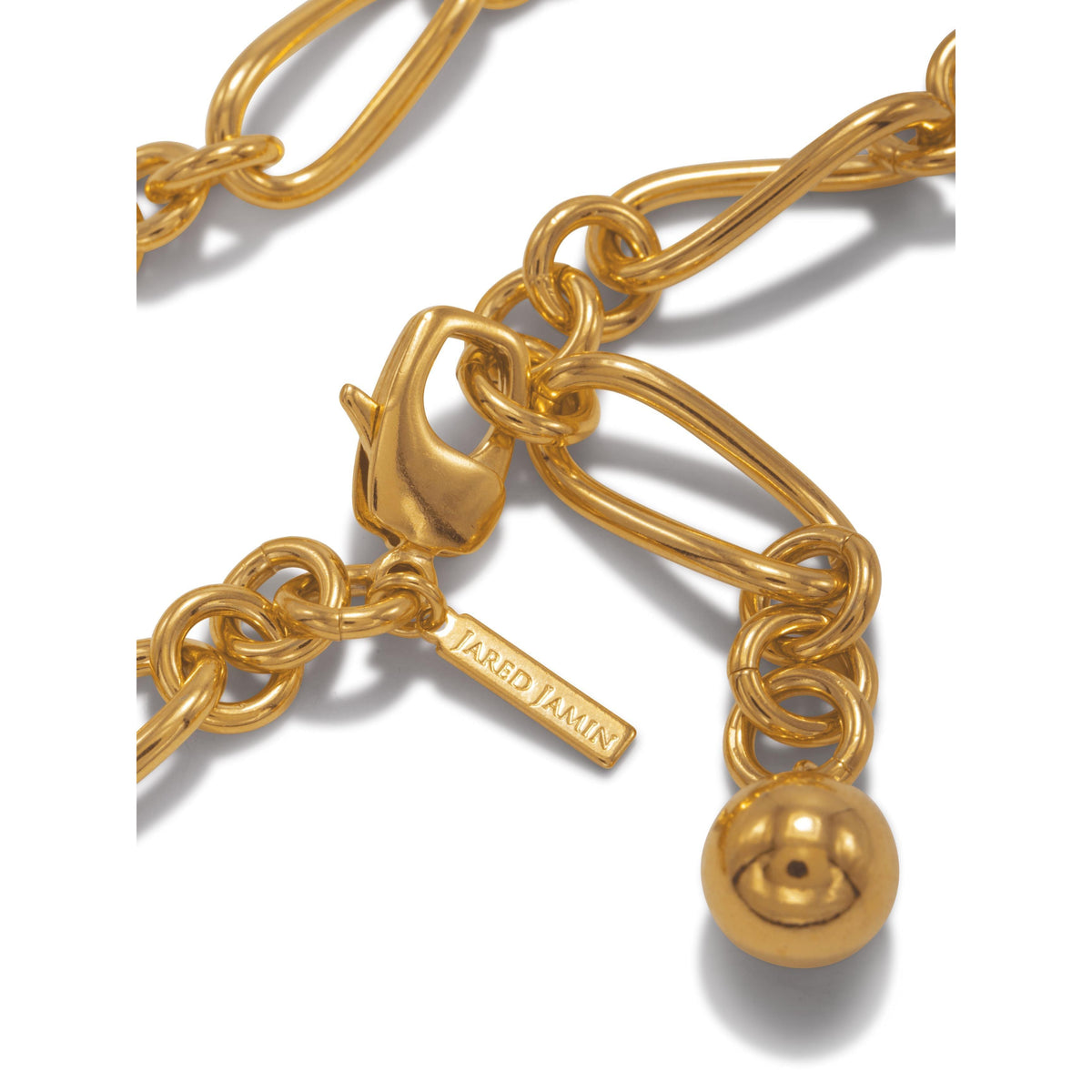 primer plano of the oro Skyler cadena pulsera de JAREDJAMIN Joyería Online, con chunky 18K bañado en oro oval y round links, lobster clasp, colgante oro sphere, y engraved rectangular tag—all pulido for classic flair sobre un fondo blanco.