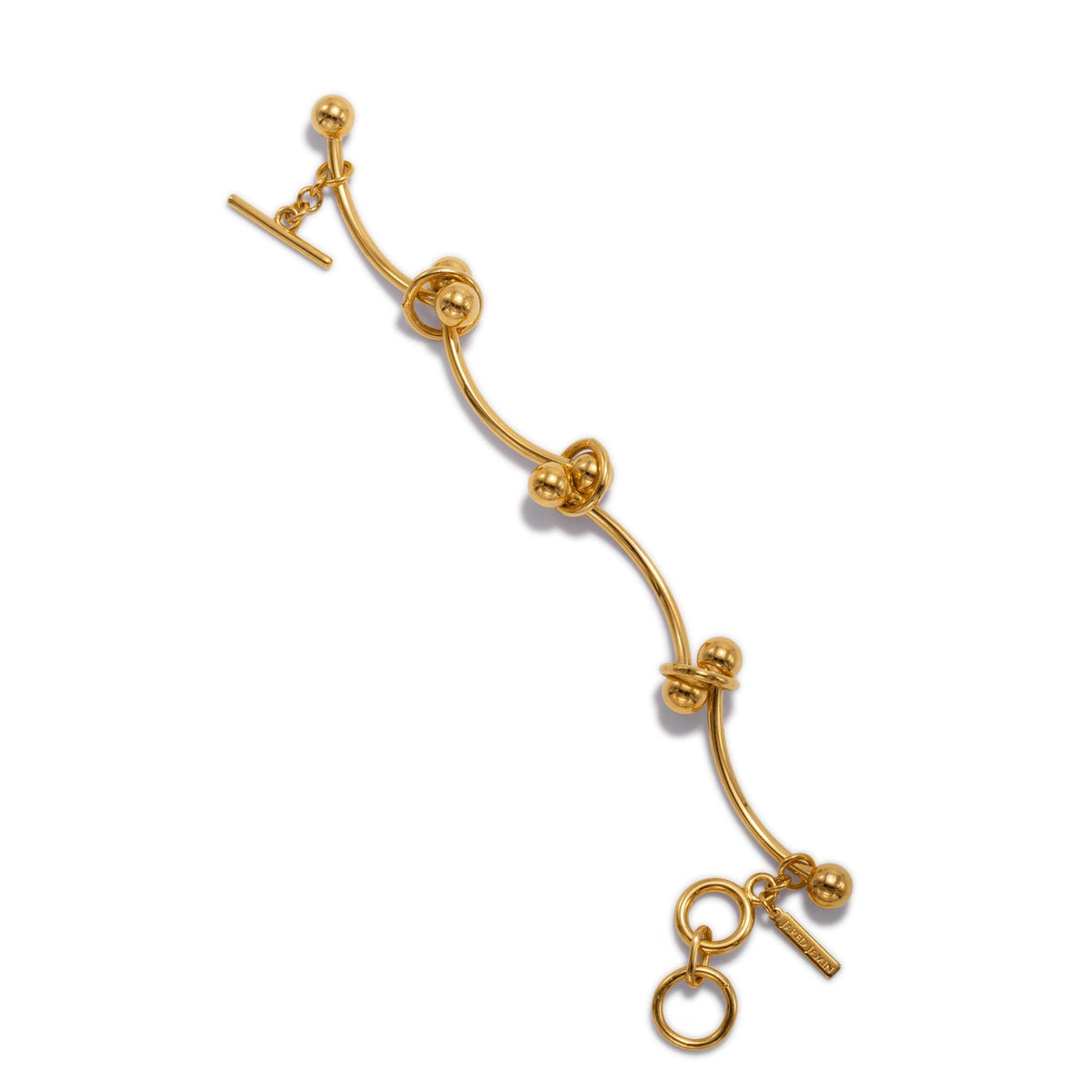 The Gold Smaller Orbita Nova Bracelet by JAREDJAMIN Jewelry Online showcases a curved 18K gold plate bar with five round beads, a toggle clasp, two interlocking rings, and a small rectangular tag, set against a white background.